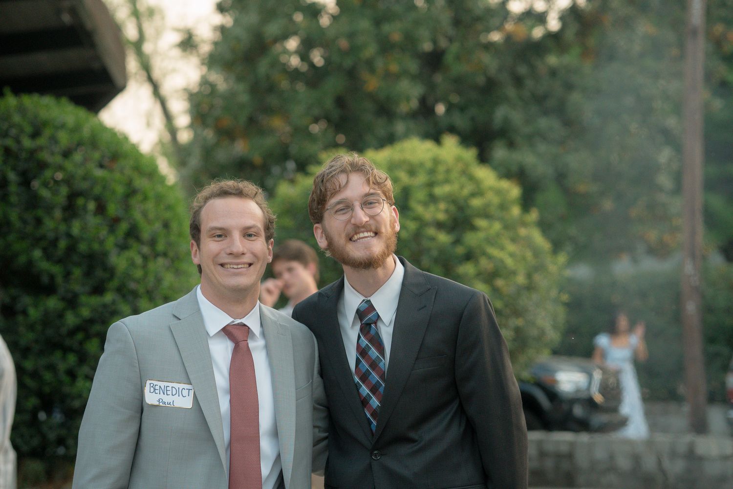 Two young men in suits smile together outdoors at a Catholic Easter Vigil in Athens, GA.