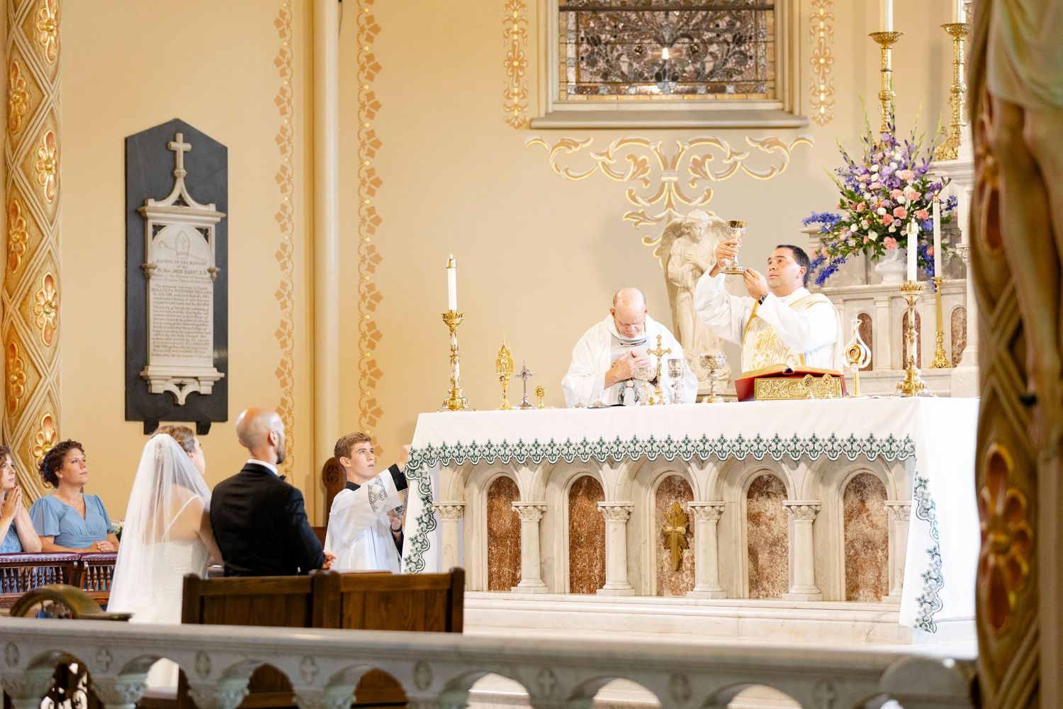 Catholic church wedding ceremony at ornate altar with bride, groom, and priest during traditional marriage rite in Augusta, GA.