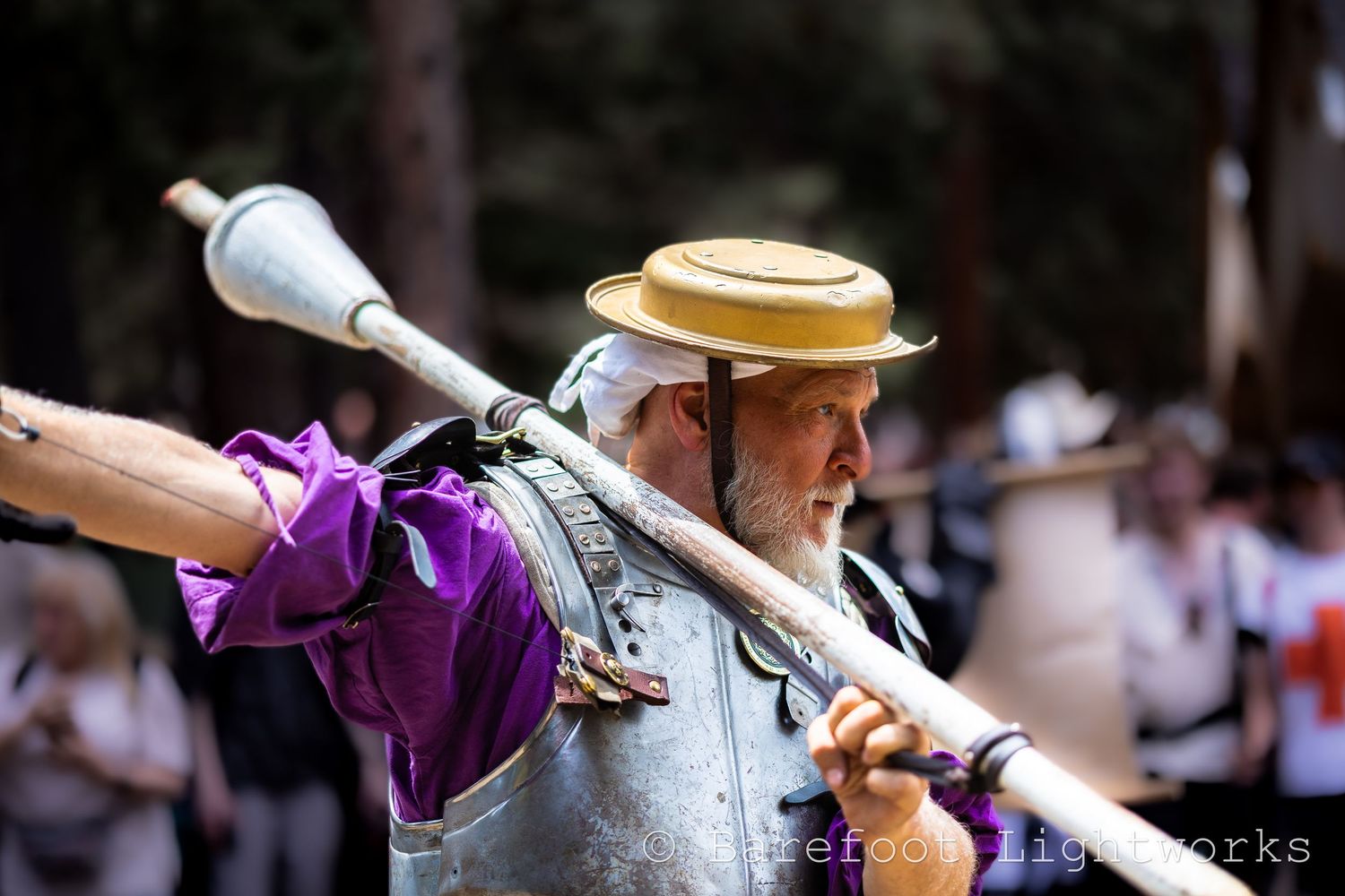 A portrait of a man at the Colorado Renaissance Fair balancing a lance on his shoulder as he walks the parade