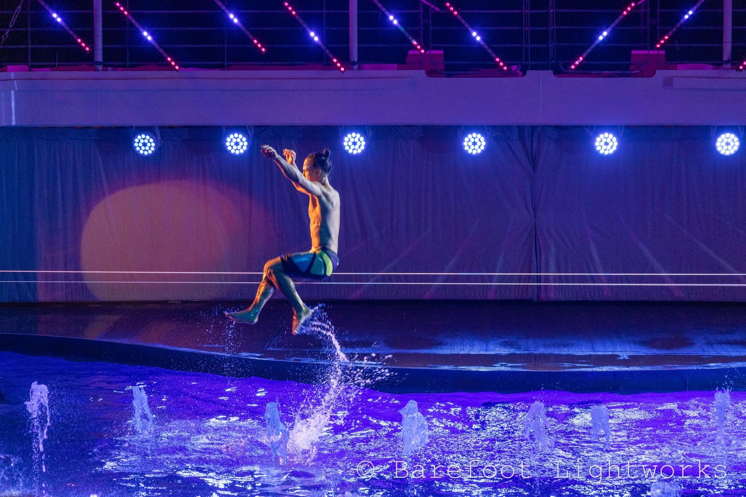 A photo of an impressive performer from a cruise ship doing a trick on a slackline