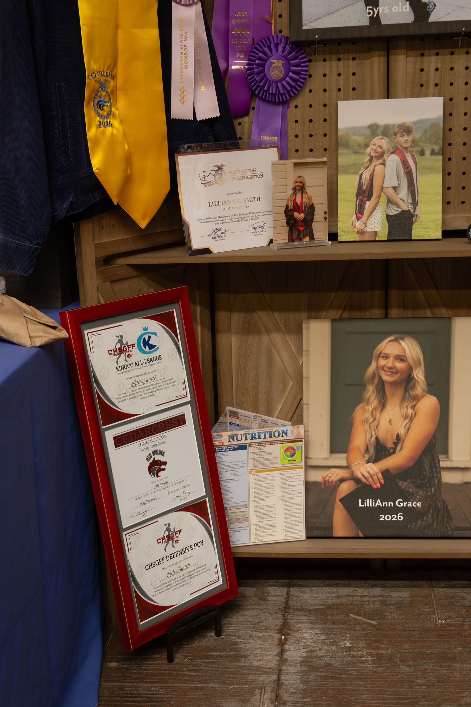 Display shelf with FFA ribbons, awards, certificates, and senior portrait for LilliAnn Grace 2026.