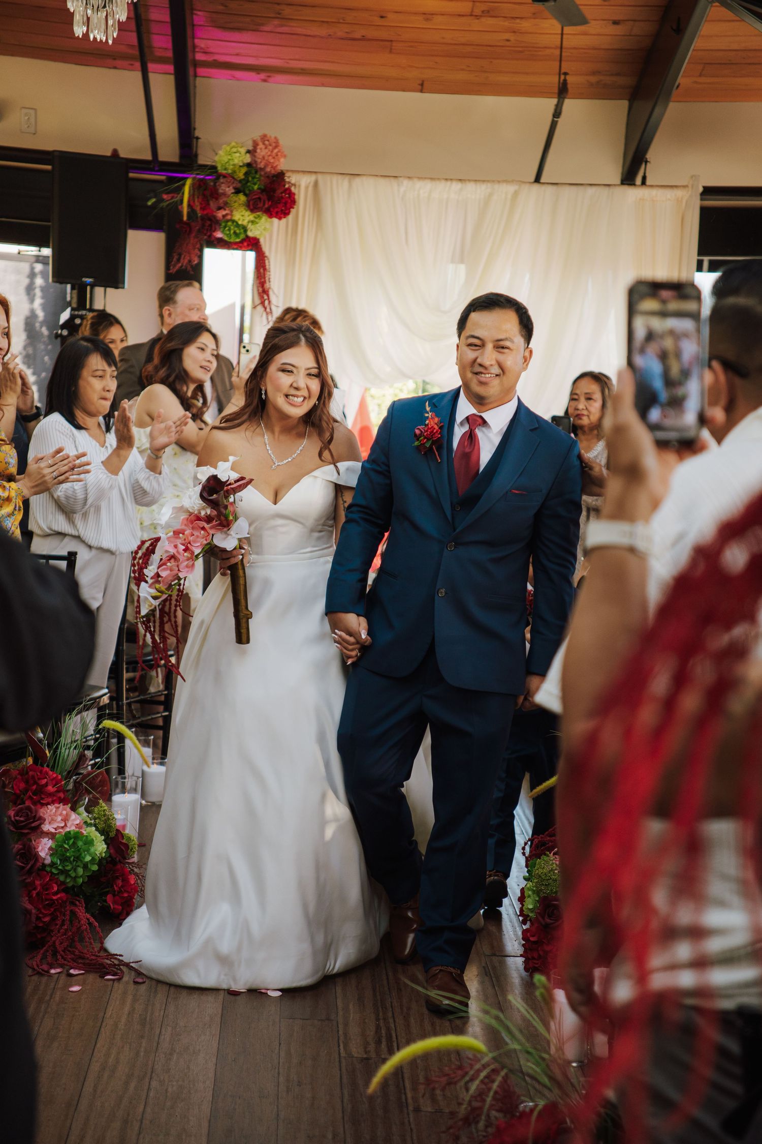 Bride and groom walk down the aisle smiling at their wedding ceremony with guests celebrating around them.