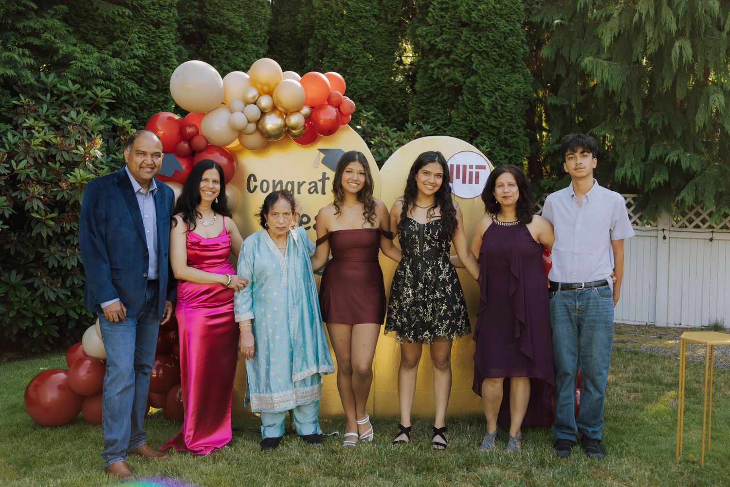 Family group photo at outdoor MIT Class of 2026 graduation celebration with balloon arch backdrop.