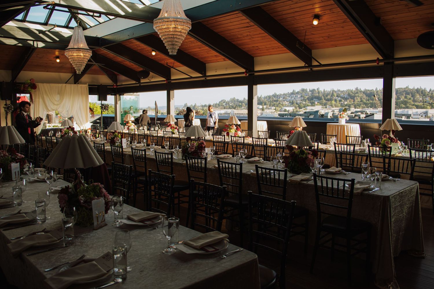 Elegant wedding reception hall with long decorated tables, Chiavari chairs, and scenic outdoor views.