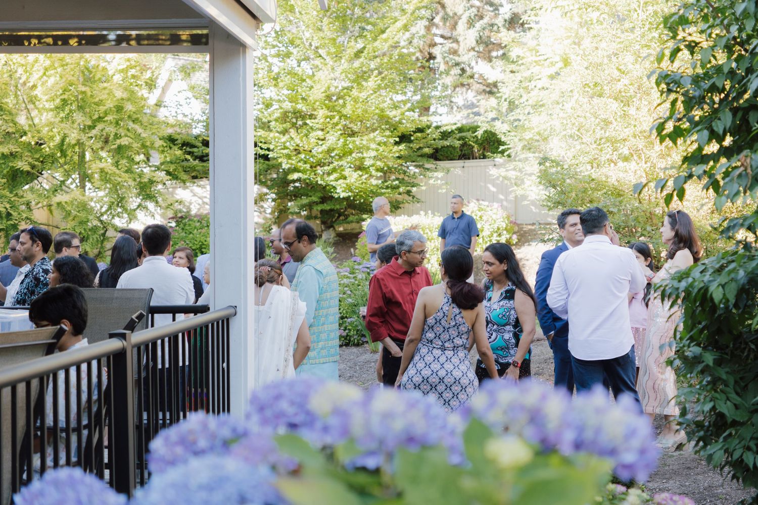 Guests socializing at an elegant outdoor garden party surrounded by hydrangeas and lush greenery.