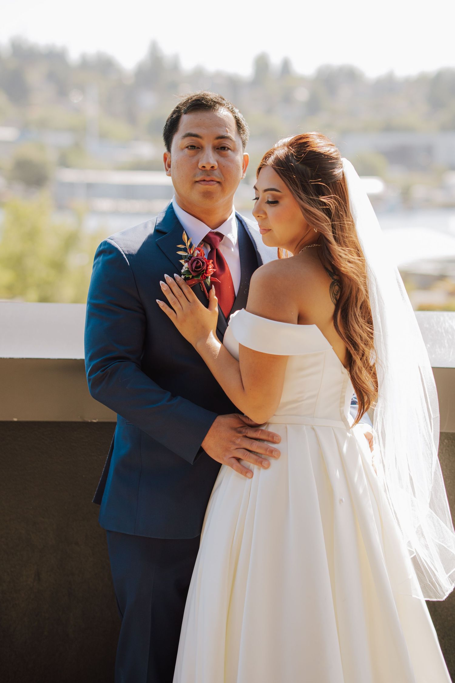 Bride and groom posing together on a rooftop terrace with a scenic backdrop.