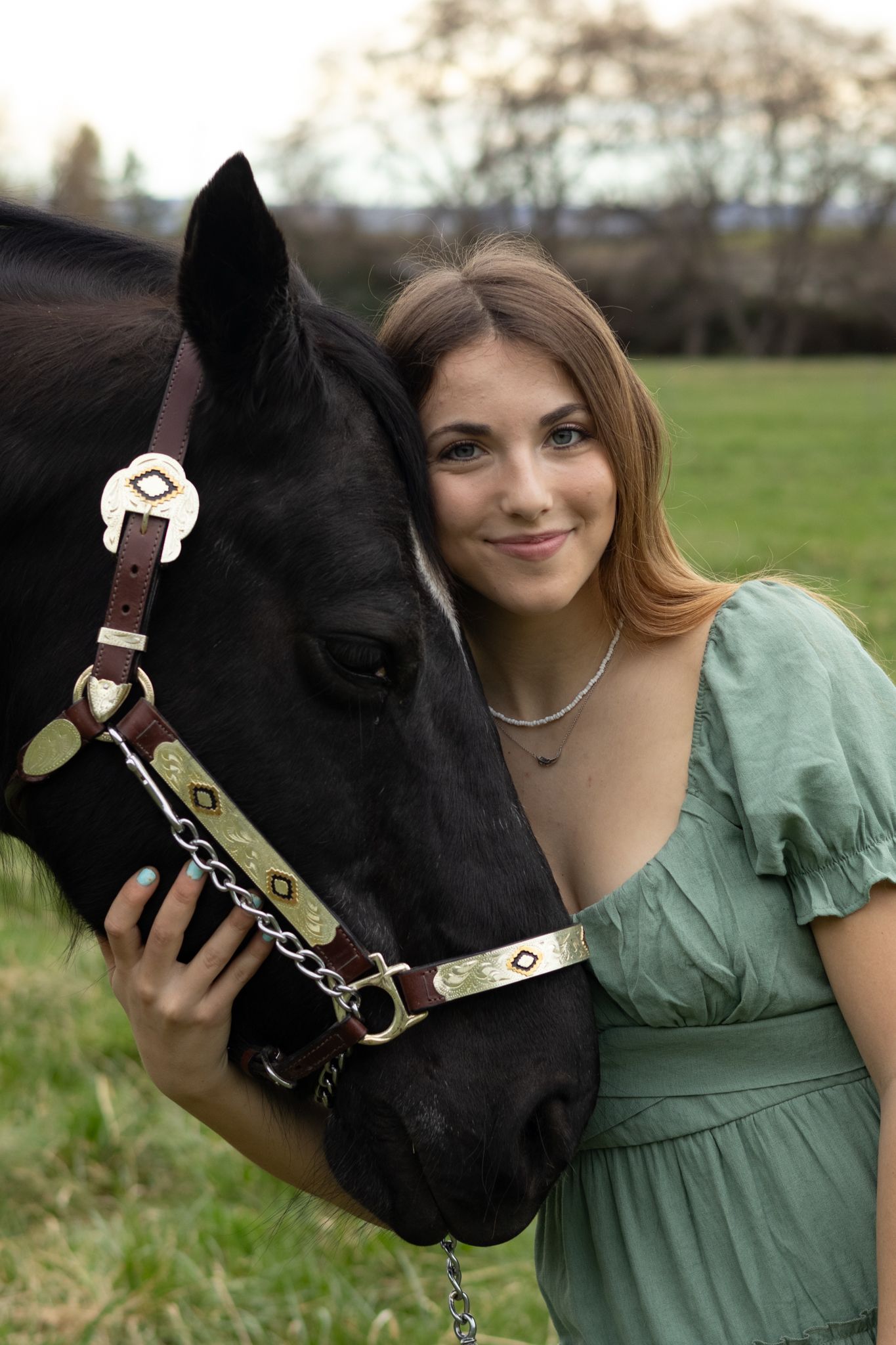 A girl and her horse stand heads together during a senior portrait photoshoot.