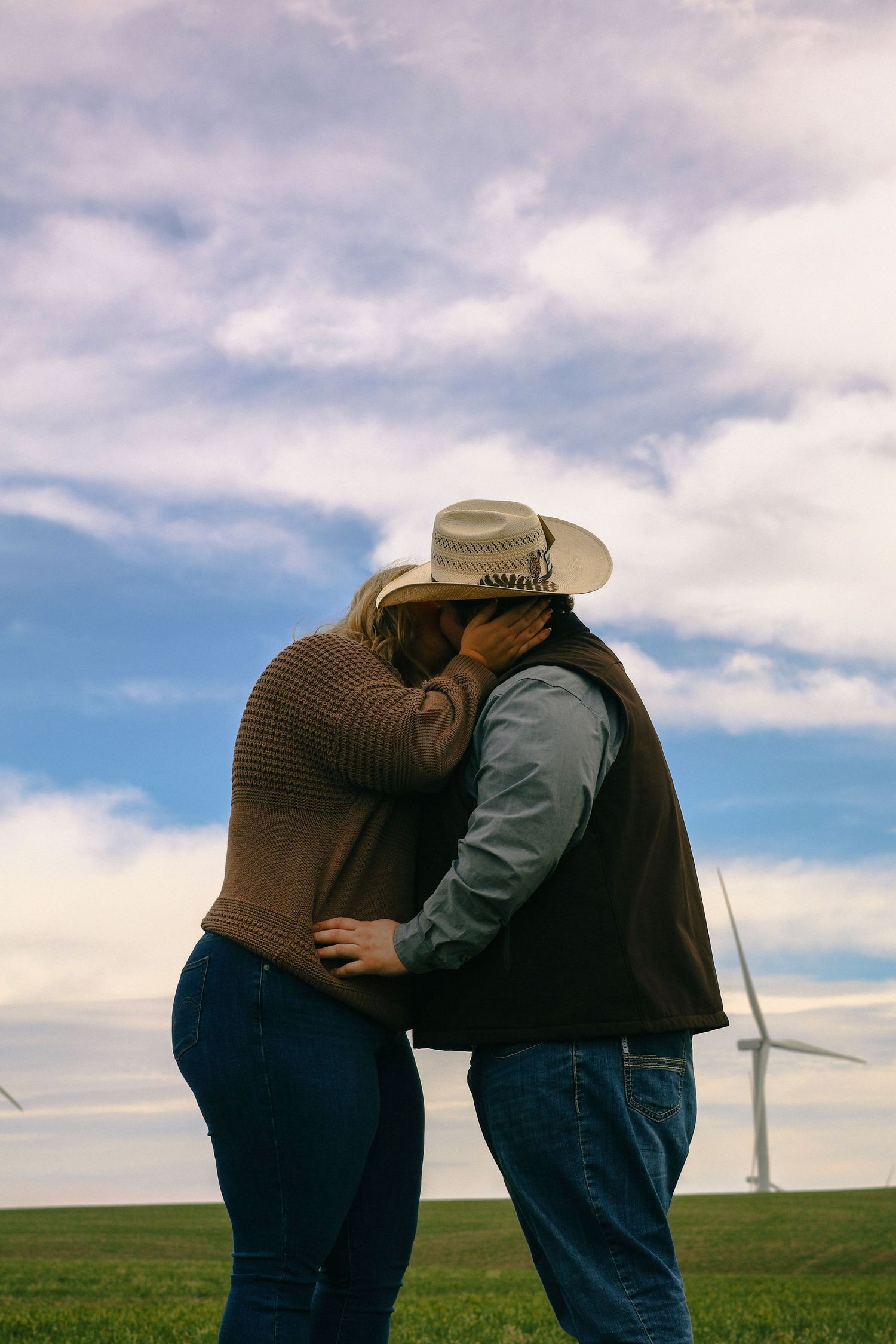 A couple kiss lovingly in Walla Walla County with windmills in the background.