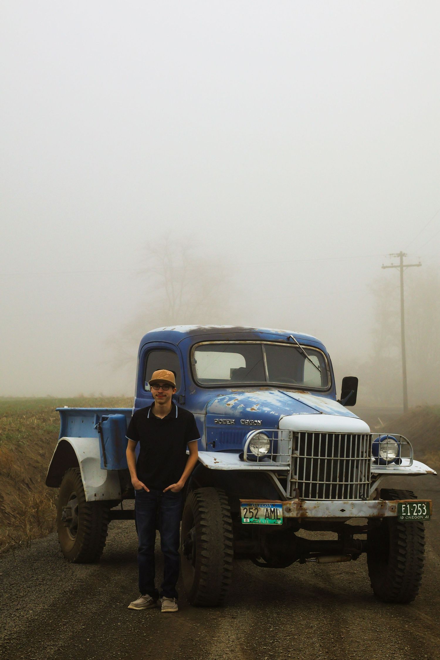 A young man poses with his old blue truck for this foggy fall senior portrait photoshoot.