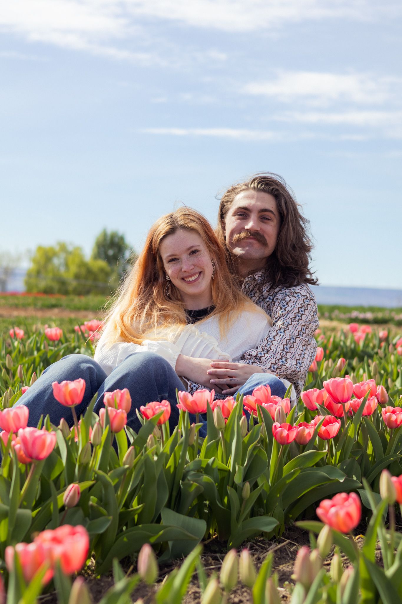 A young couple pose holding each other in the Tulip Fields of Eastern Washington.