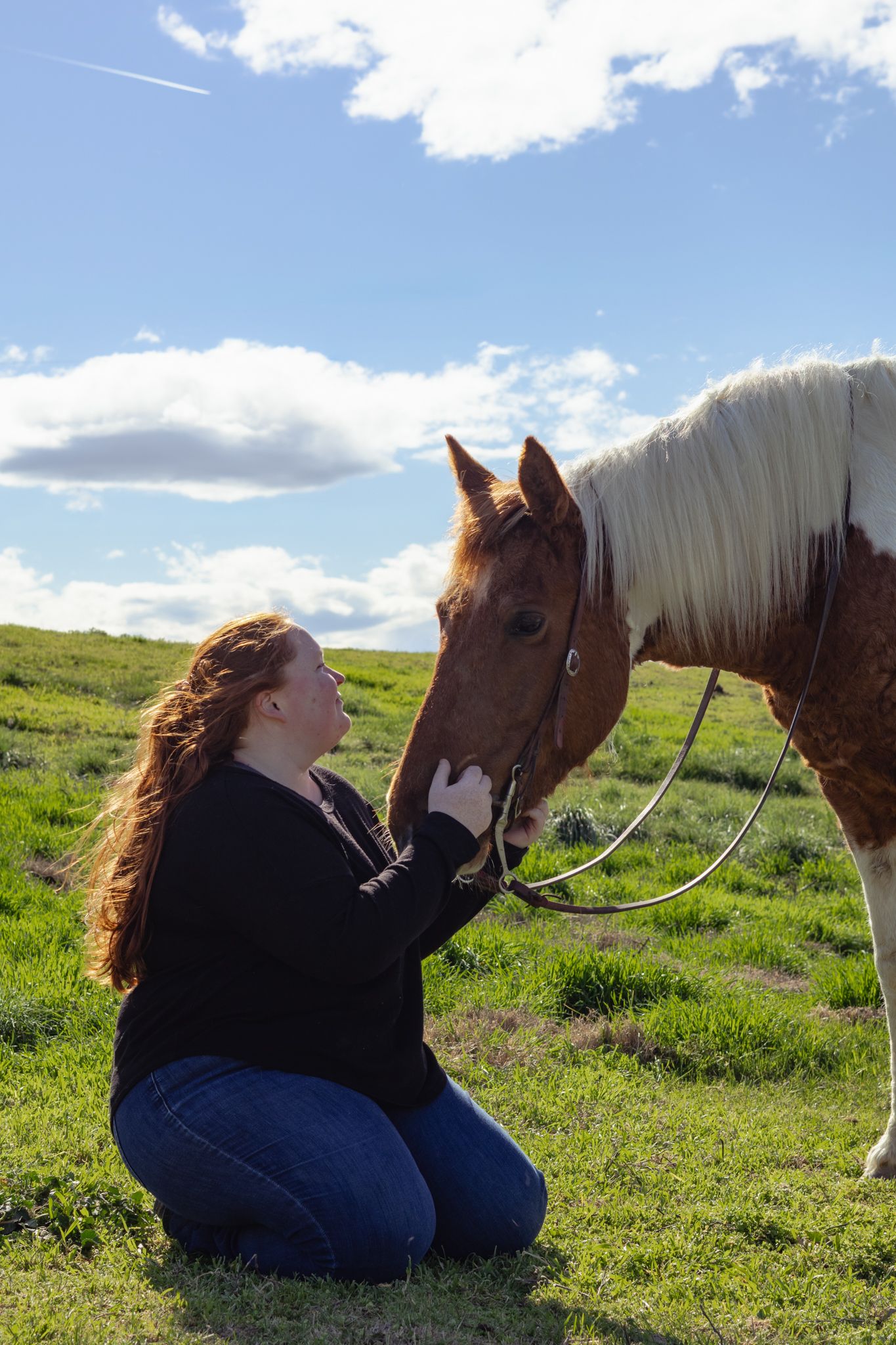 This young girl holds her paint horses face during her senior portrait photo session.