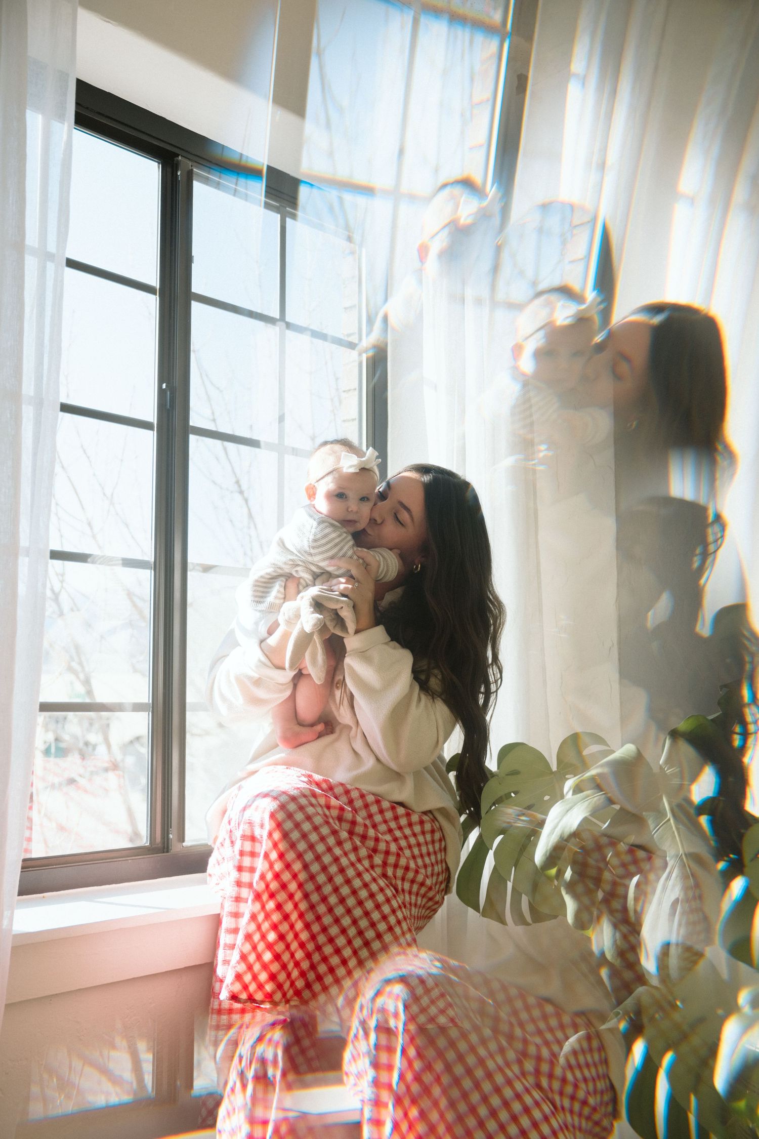 mom in a window kissing her baby