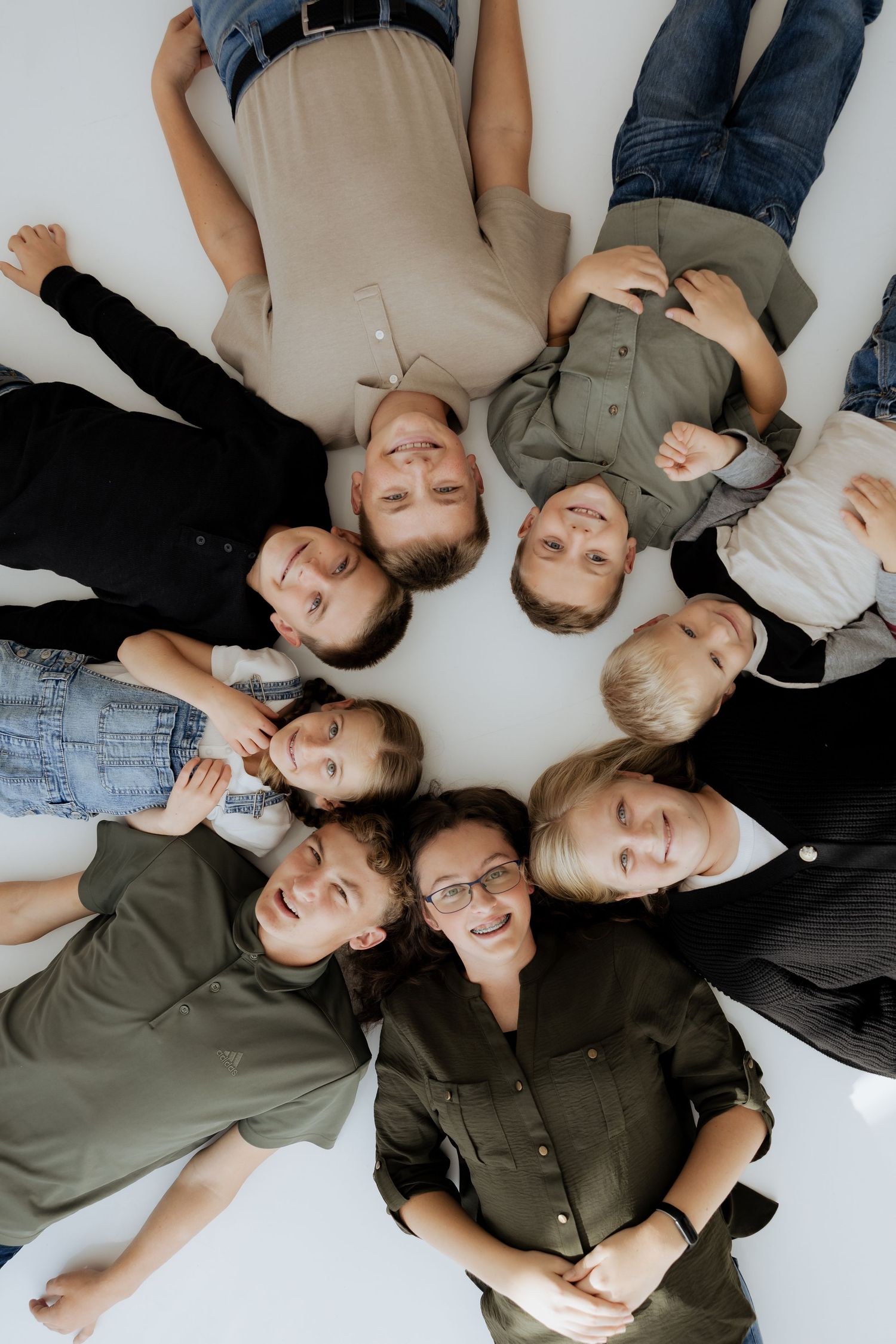 Overhead view of woman with glasses and eight children lying in a circle.