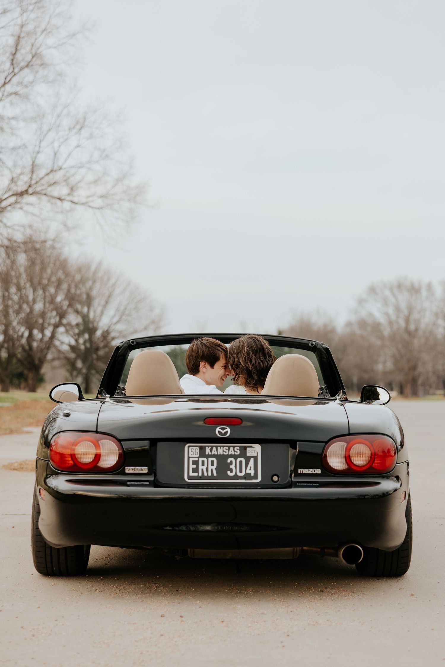 Black Mazda Miata convertible with Kansas license plate ERR 304 parked on road.
