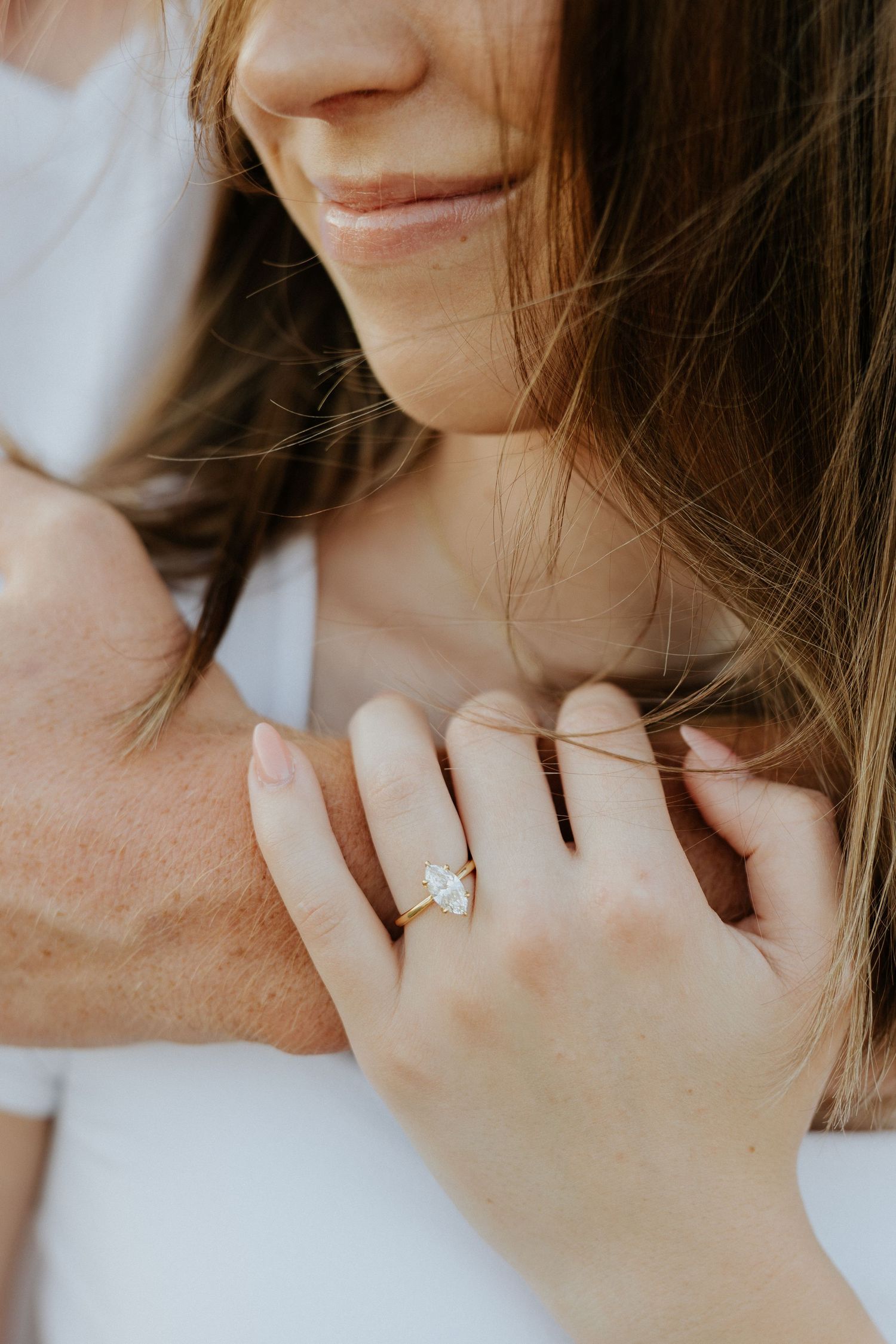 Close-up of a smiling woman displaying a stunning marquise diamond engagement ring.