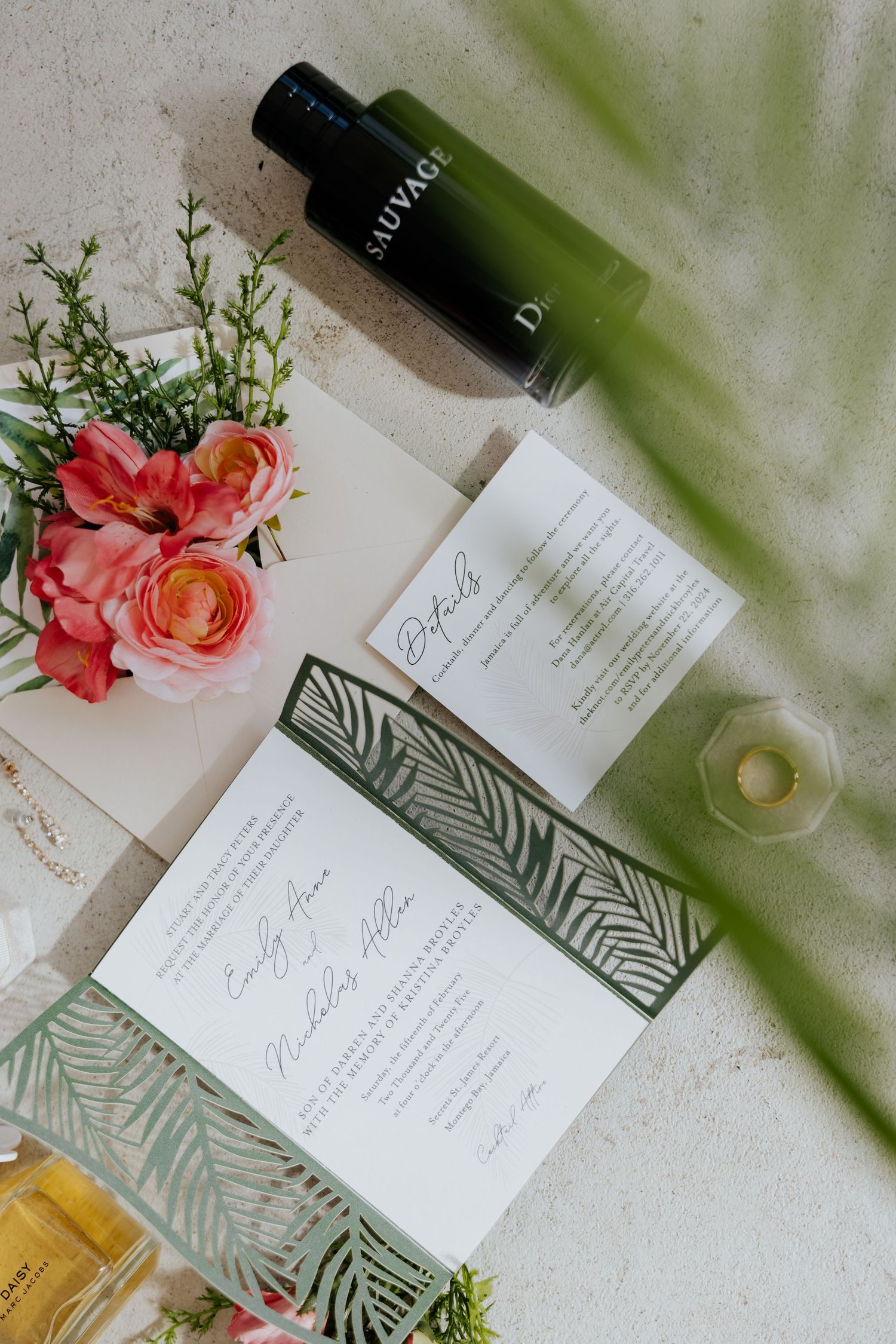Flat lay of wedding invitation suite with pink flowers, Dior cologne, and botanical stationery.