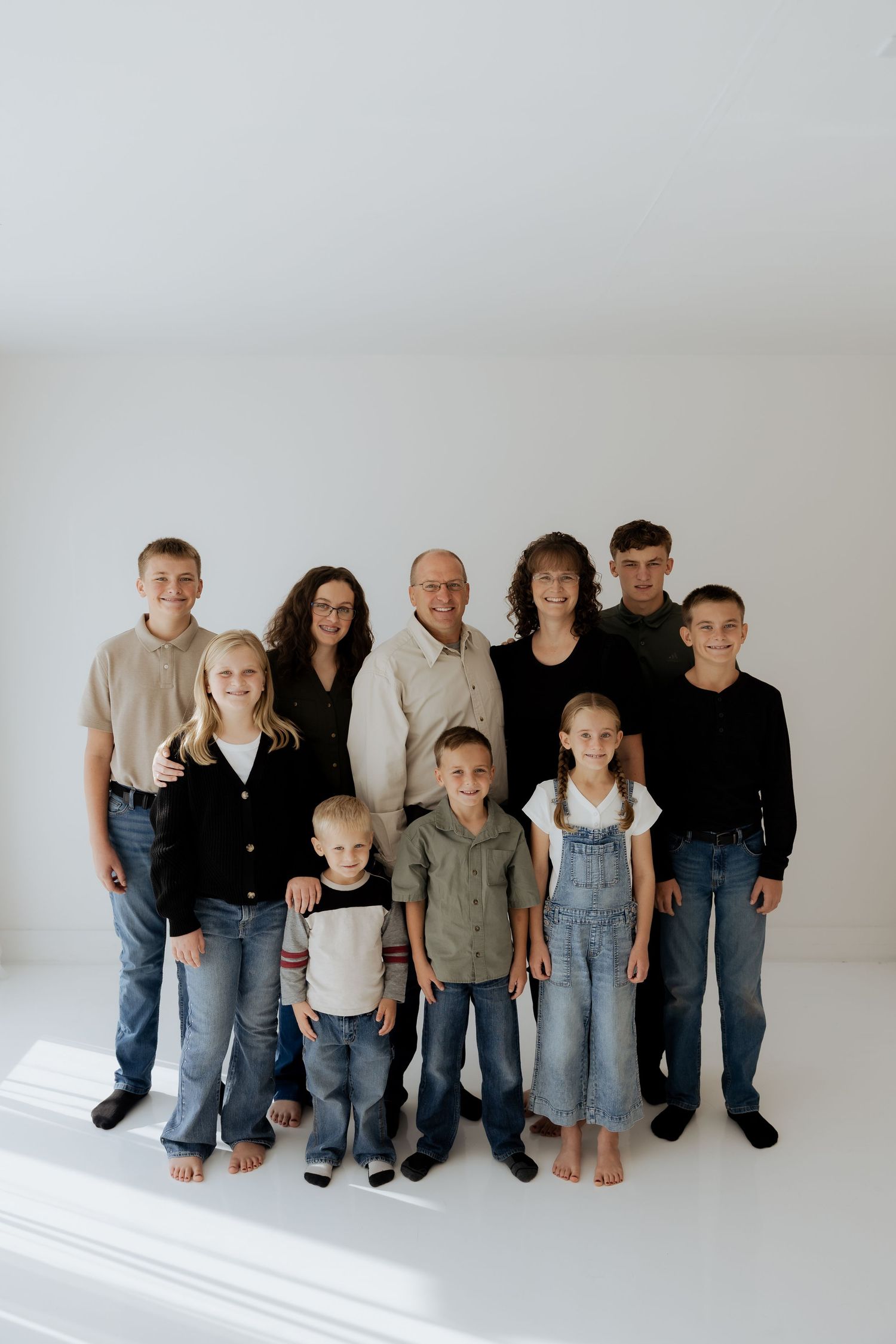 Large family group portrait with grandparents and seven children against white background.