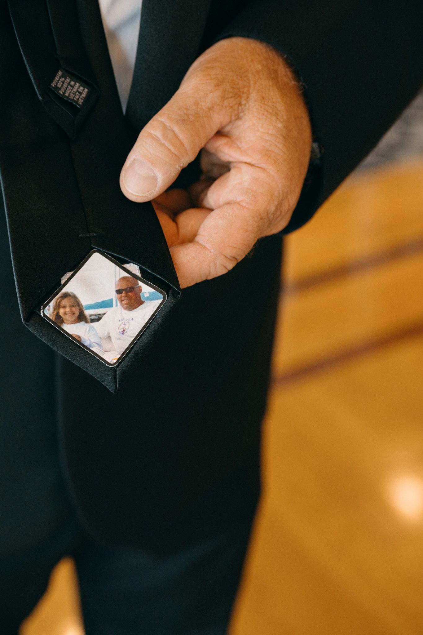 Groom holding tie clip with sentimental family photo at wedding ceremony.