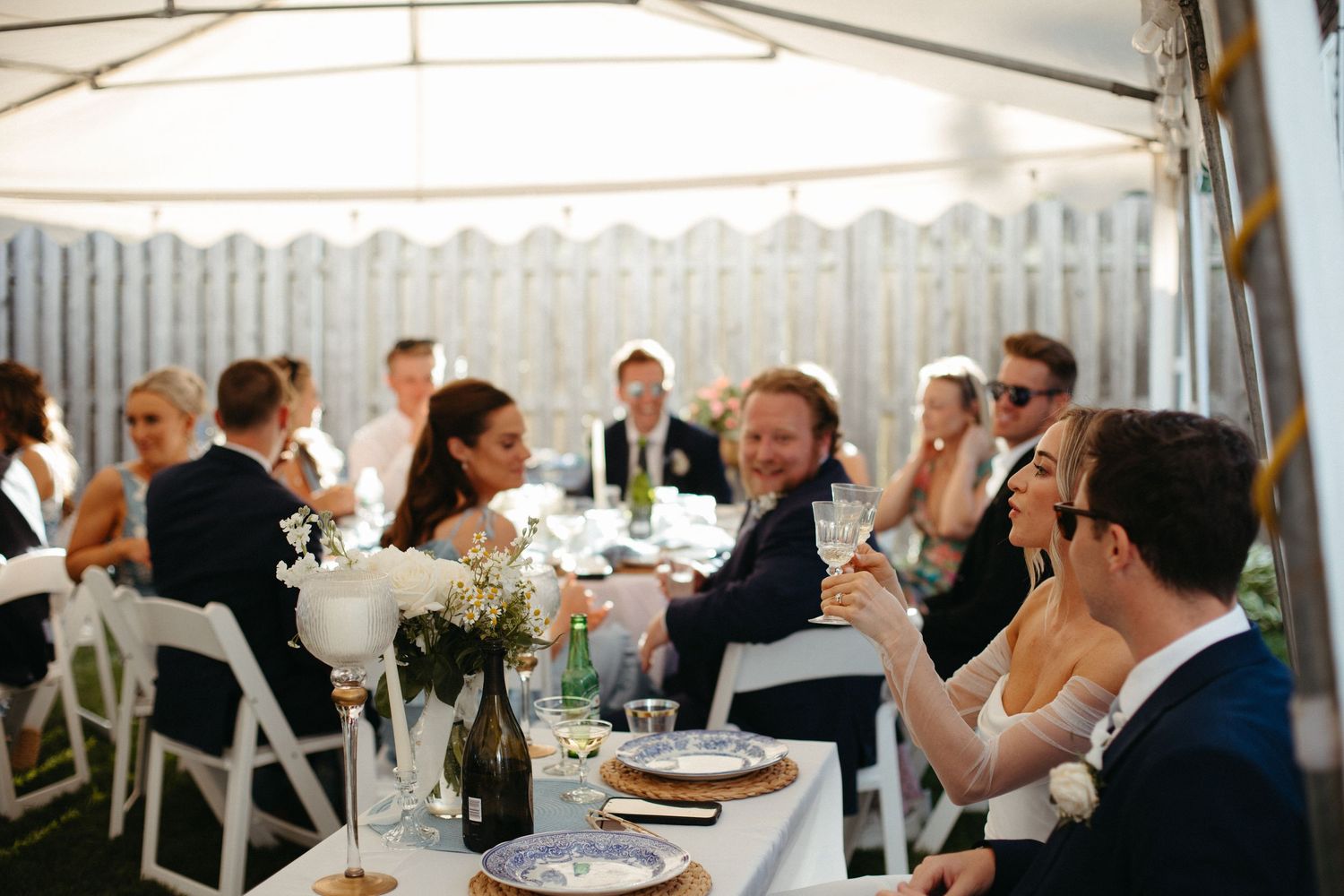 Wedding guests laughing and celebrating together at elegantly decorated outdoor tented reception table.