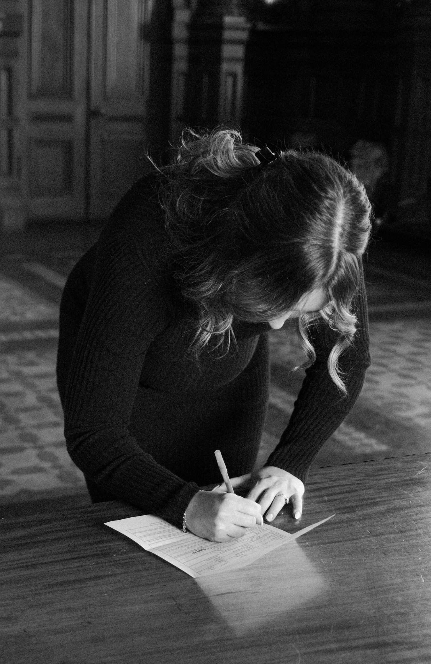 best friend signing documents on a wooden table, black and white photography.film-inspired