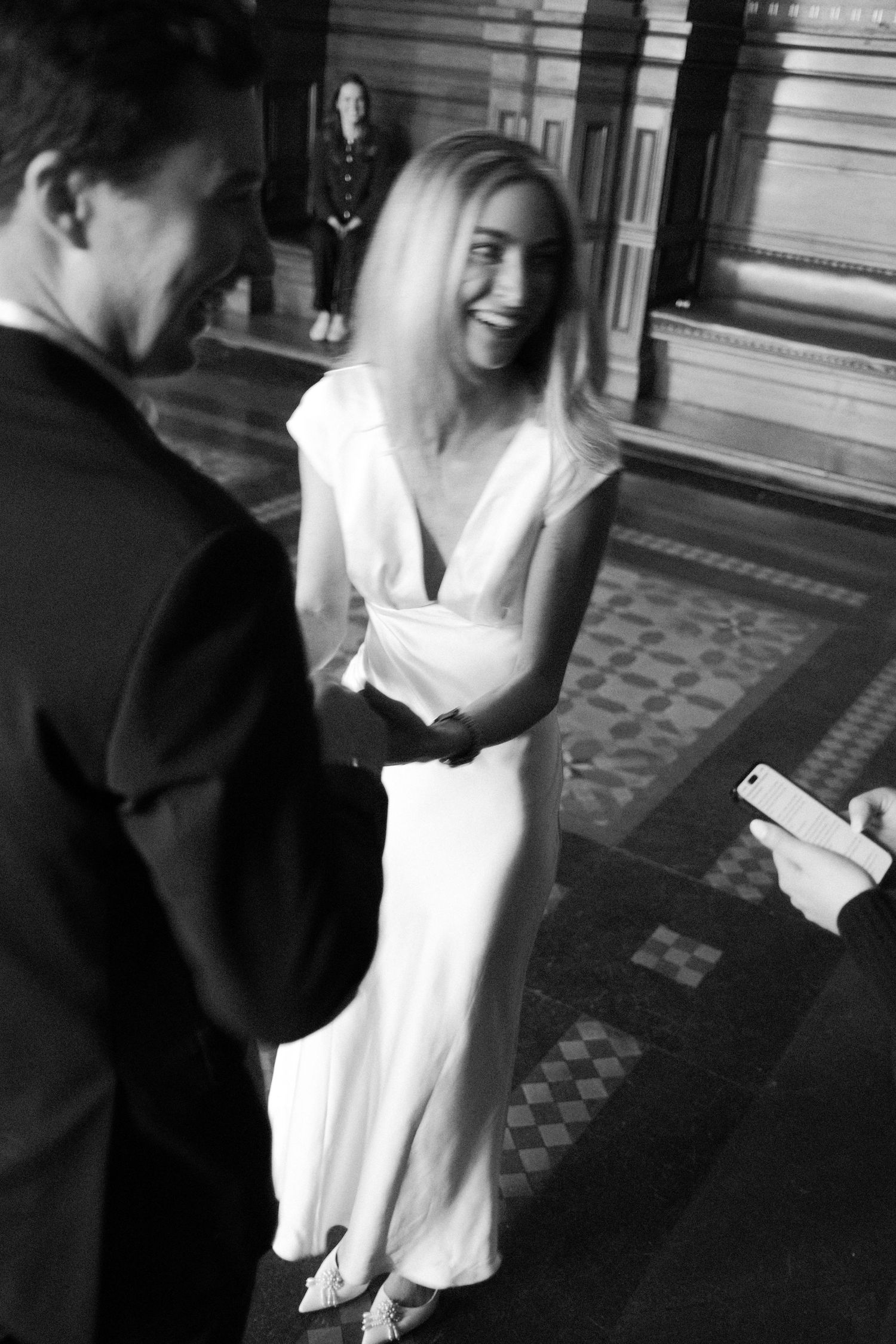 Joyful bride laughing with groom during civil wedding ceremony in grand hall.film-inspired