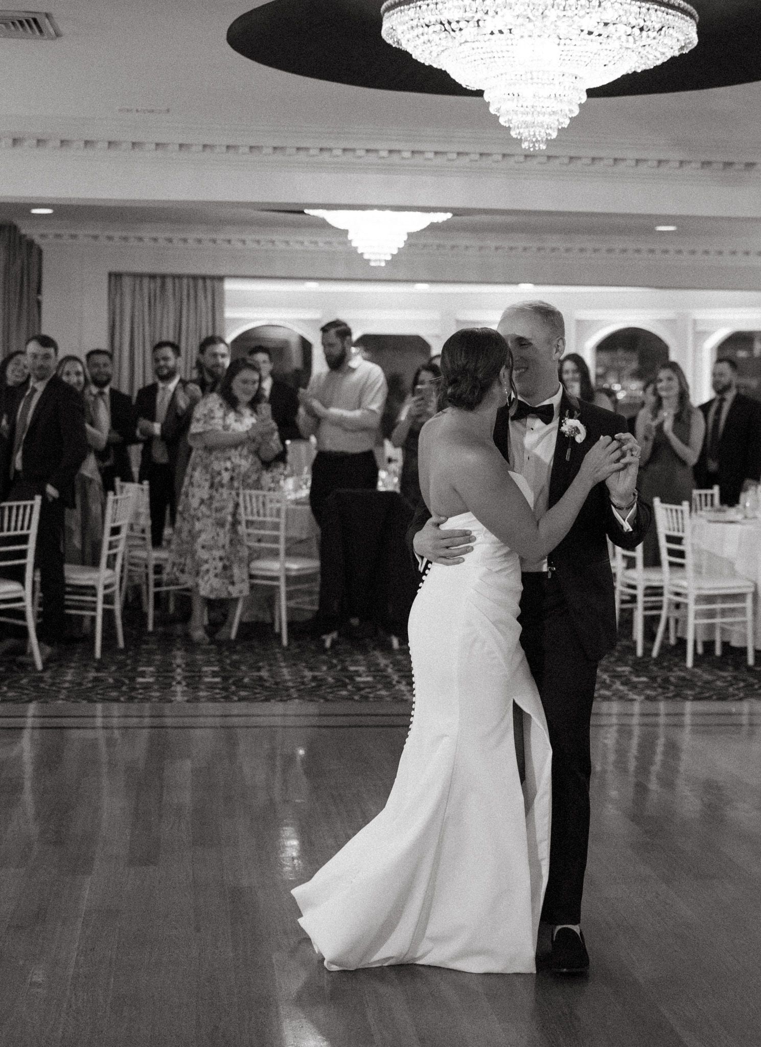 Black and white photo of bride and groom sharing first dance at wedding reception.