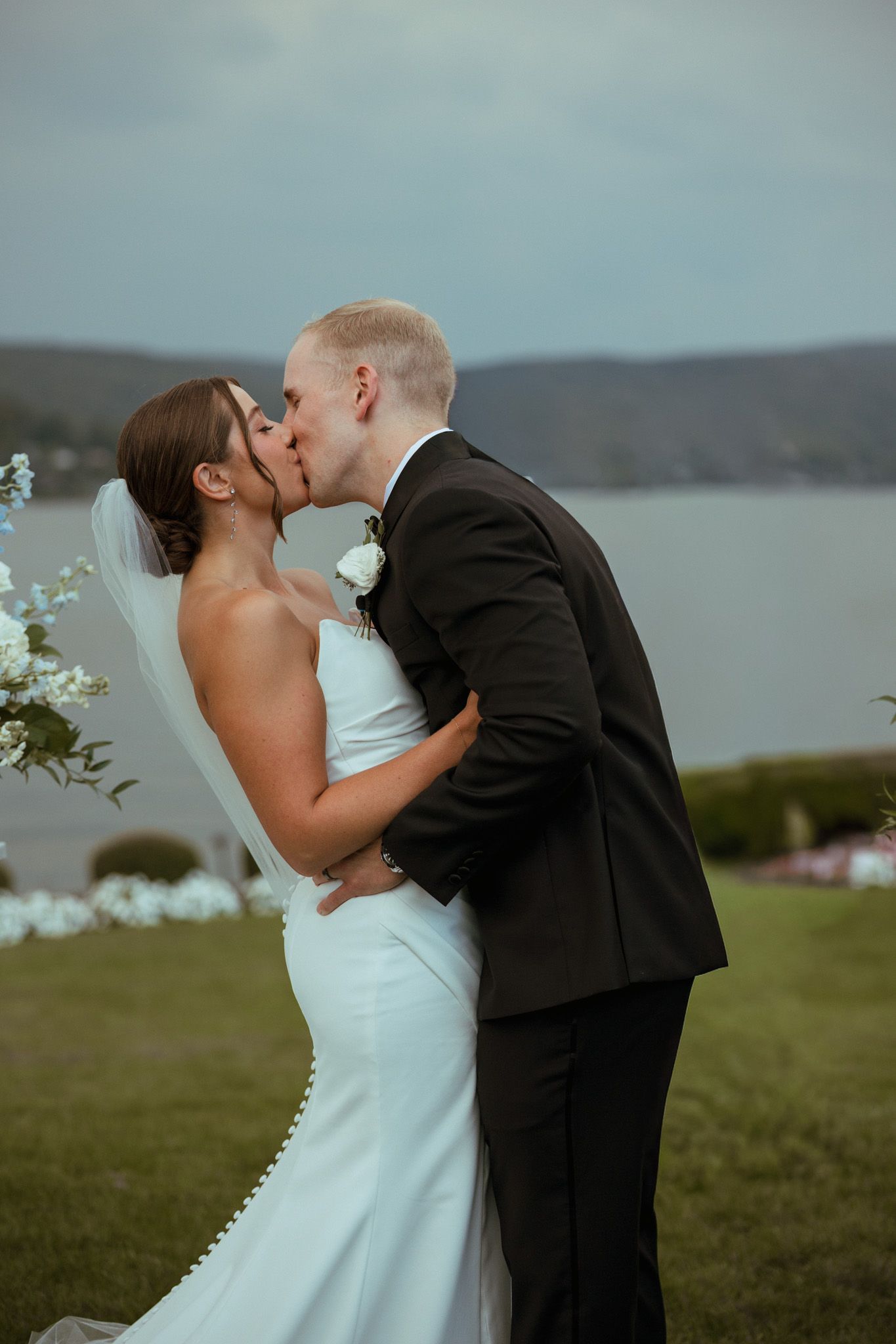 Bride and groom share their first kiss at outdoor waterfront wedding ceremony.