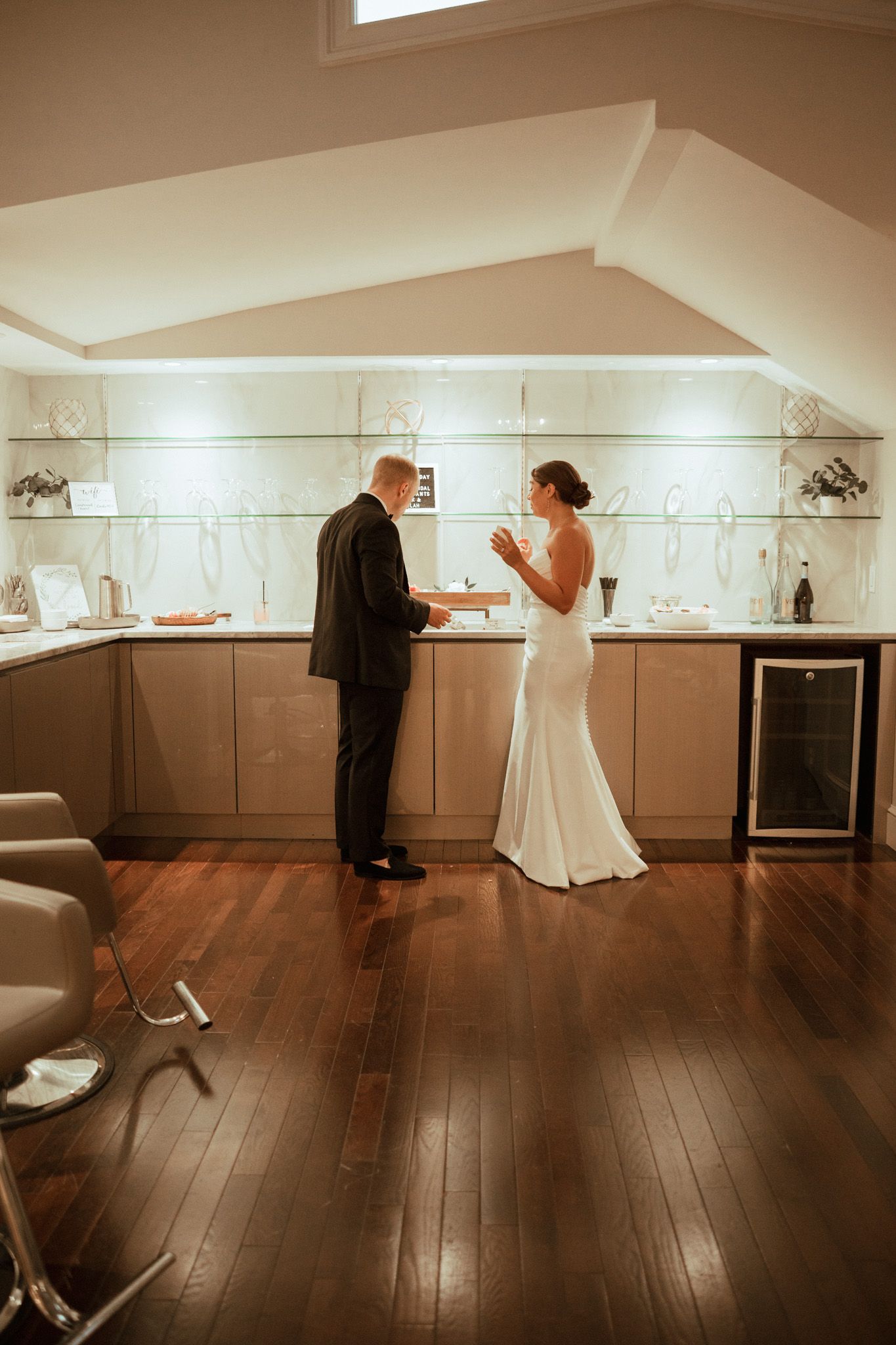 Bride and groom share a private moment exchanging vows in an elegant modern venue with warm lighting.