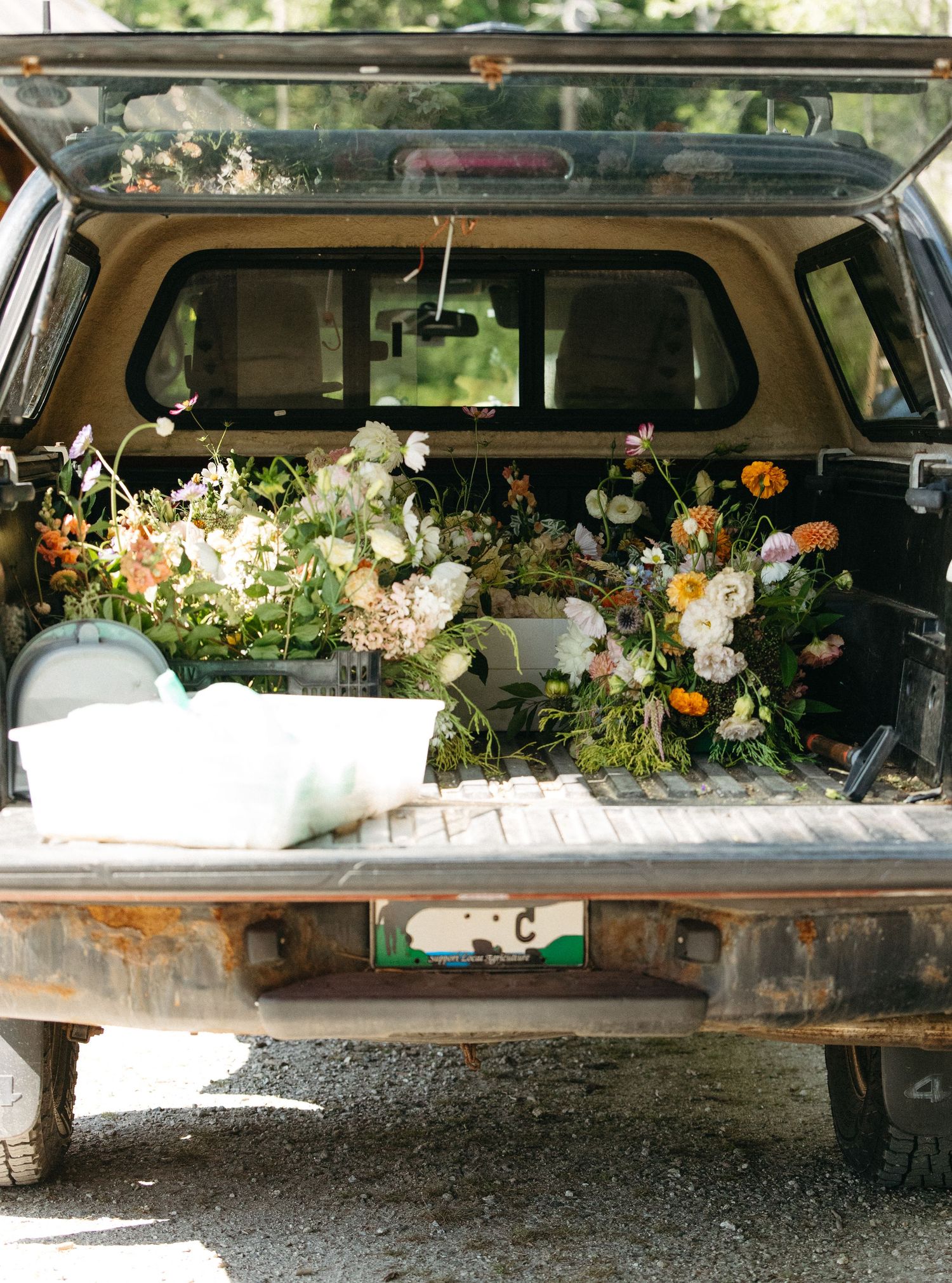 Colorful wedding flowers arranged in rustic truck bed for floral delivery.