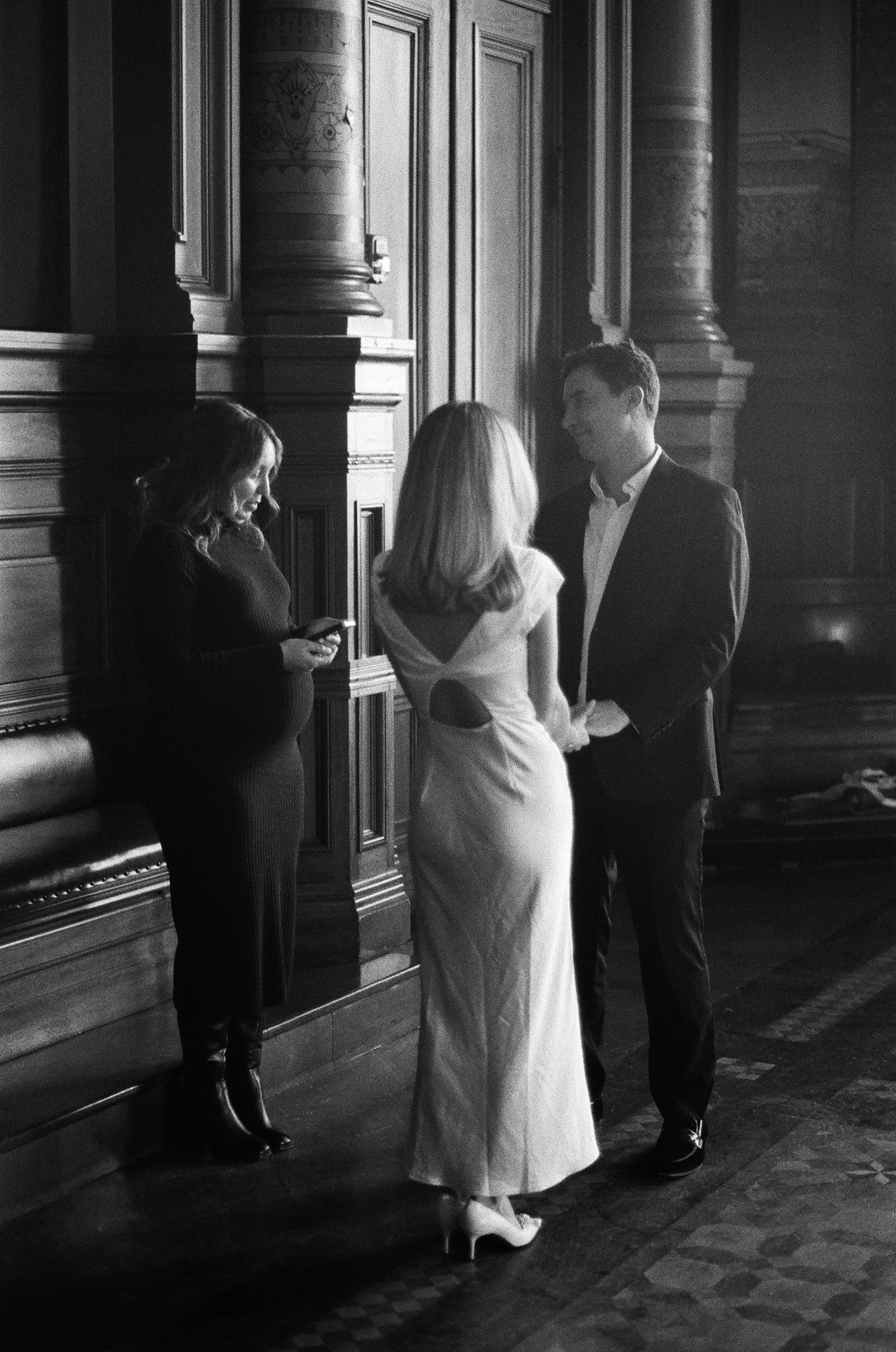 Bride in simple elegant white dress exchanges vows with groom while officiant reads from book indoors. 90s romantic vibe, shot on film.
