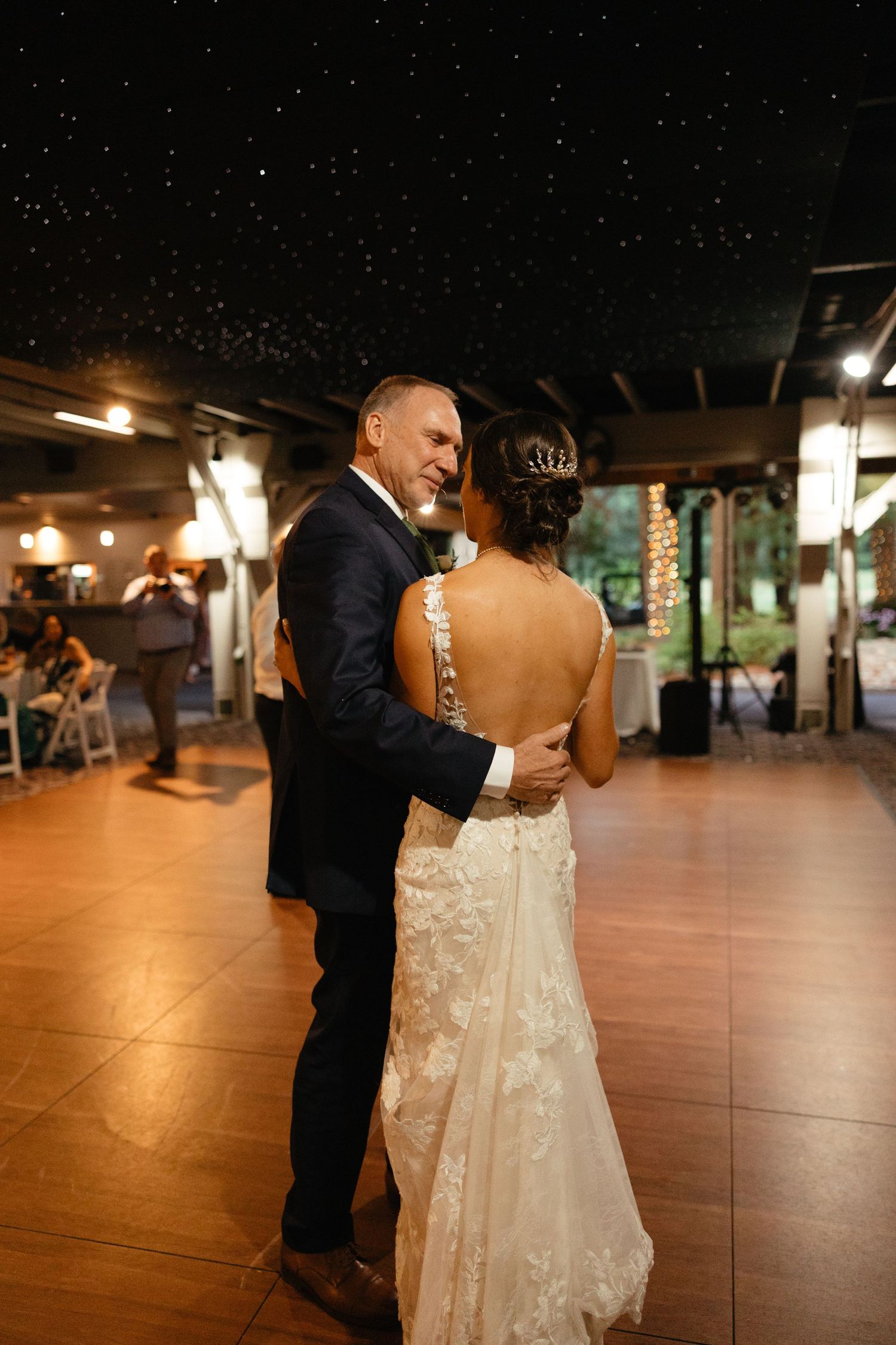 Bride and father share an emotional first dance at wedding reception under starry ceiling.film-inspired