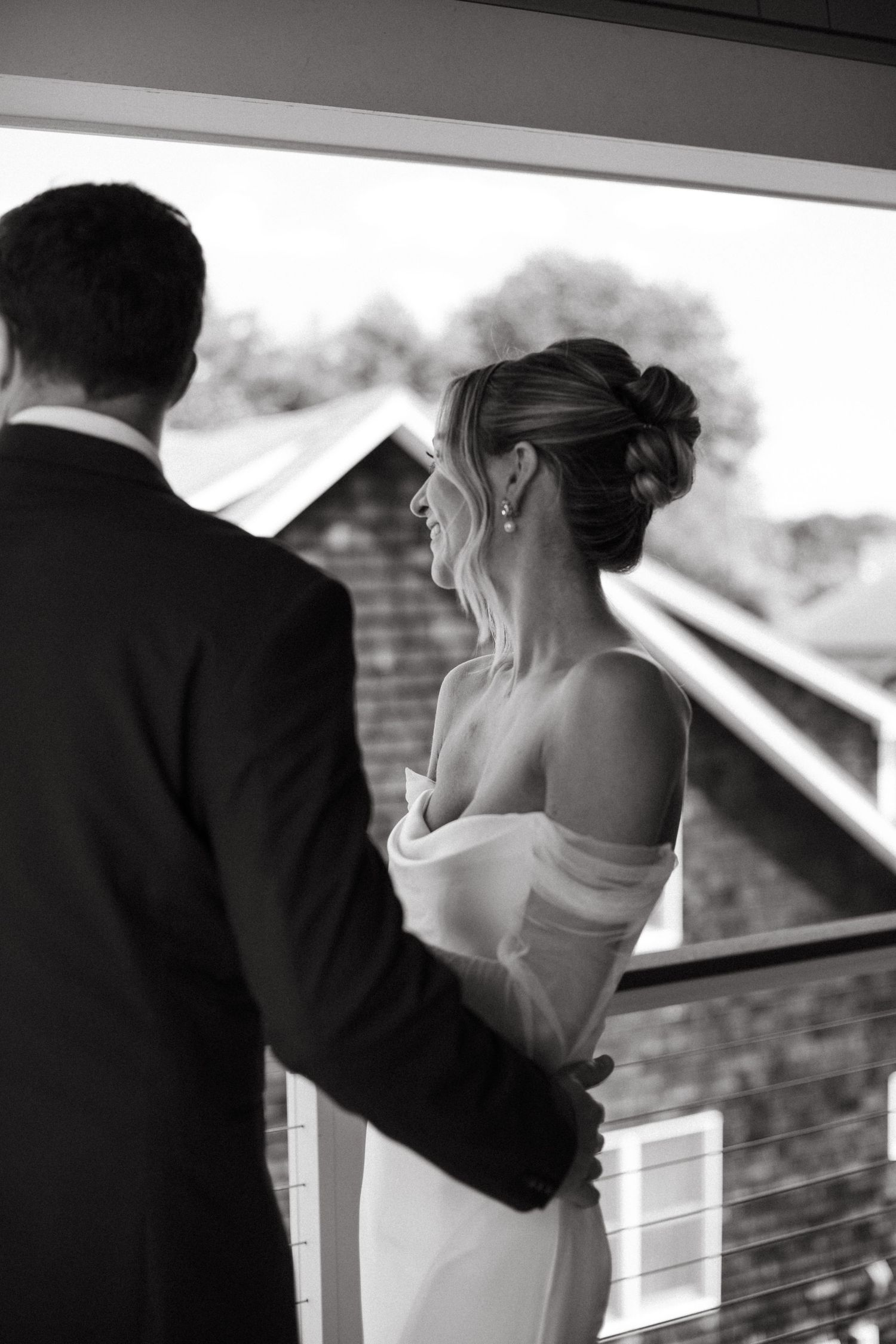 Black and white photo of bride and groom sharing romantic moment on balcony.