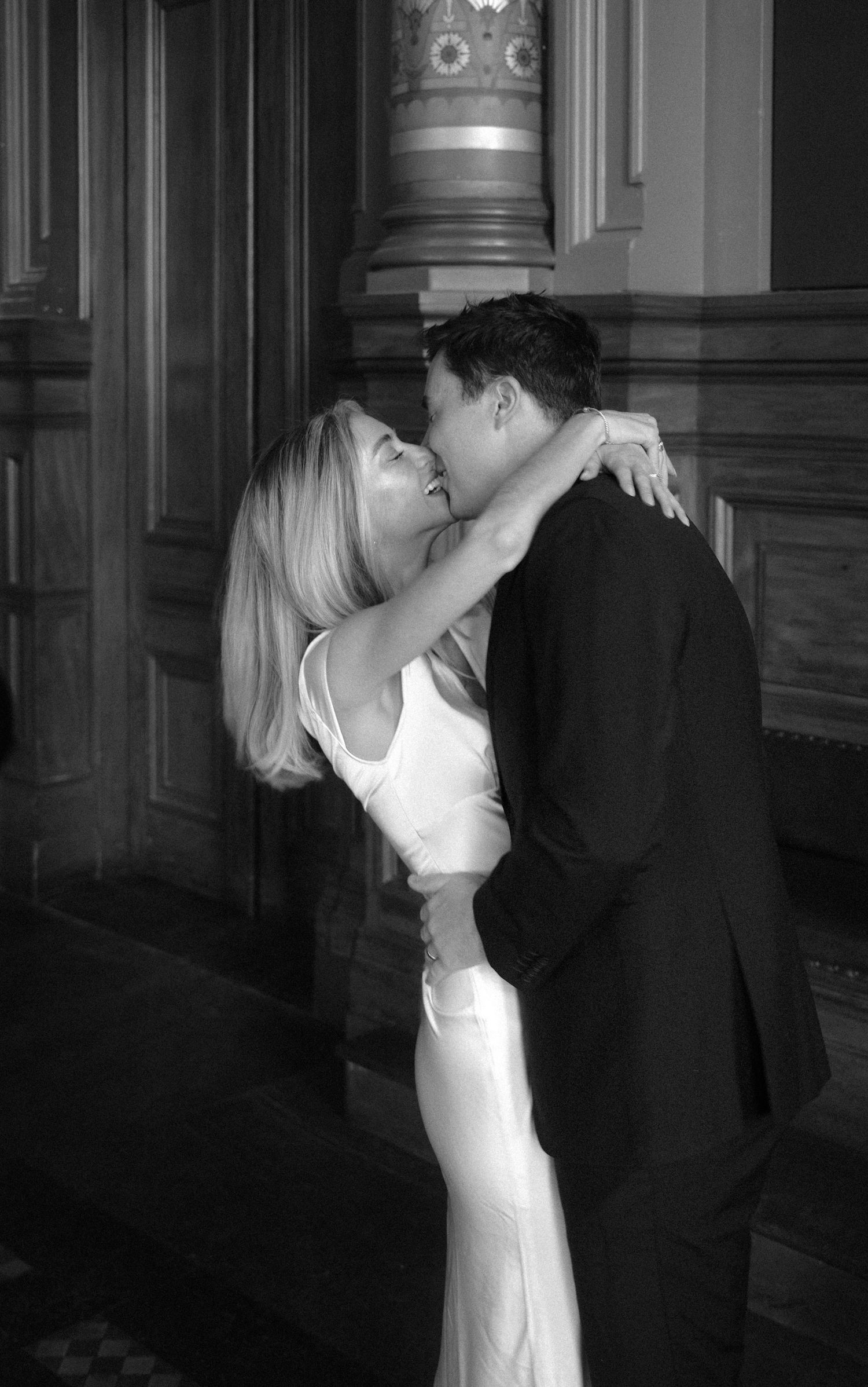 Newlyweds sharing first kiss after civil wedding ceremony in historic building.film-inspired