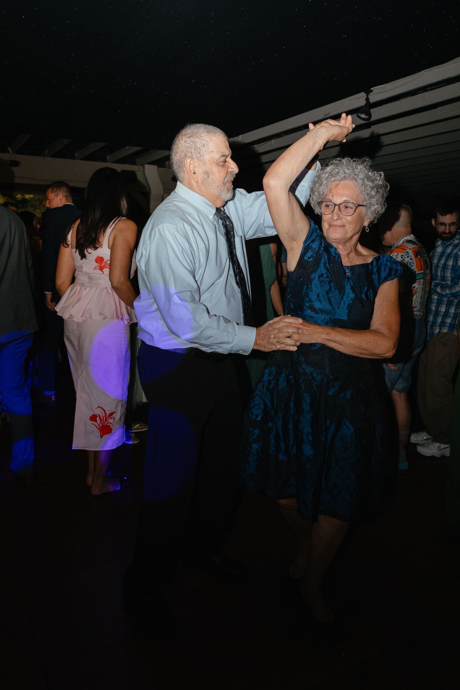 Elderly couple dancing joyfully at wedding reception celebration on dance floor.film-inspired