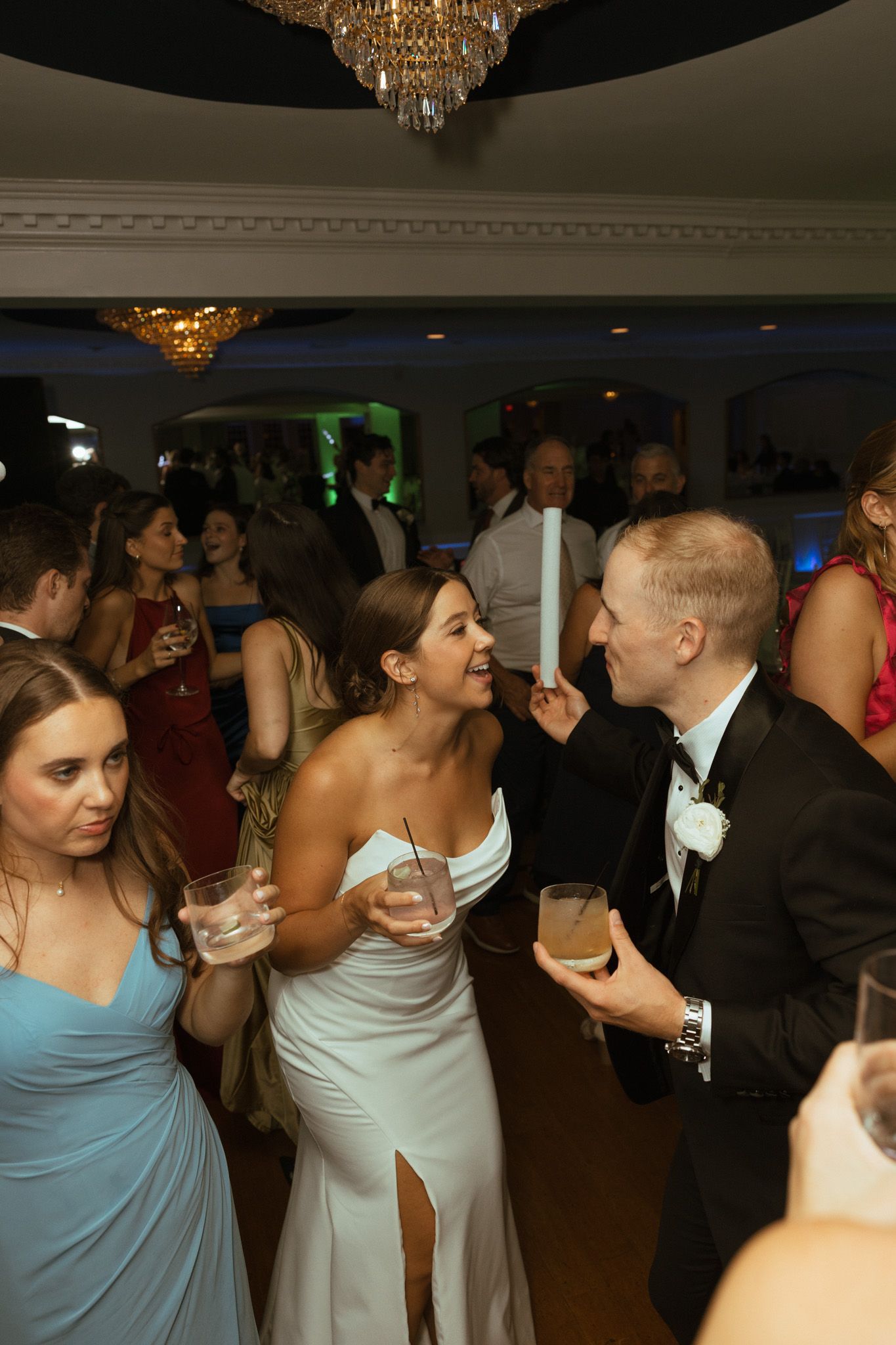 Bride and groom sharing a joyful moment while holding drinks on the wedding reception dance floor.