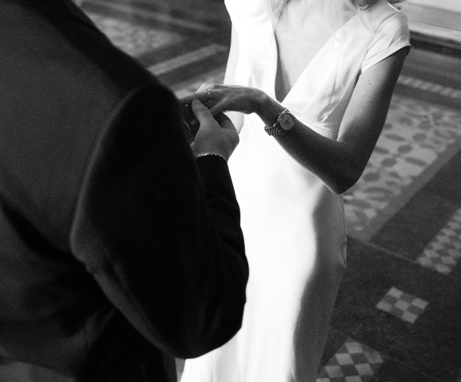 Groom placing wedding ring on bride's finger during civil ceremony.film-inspired