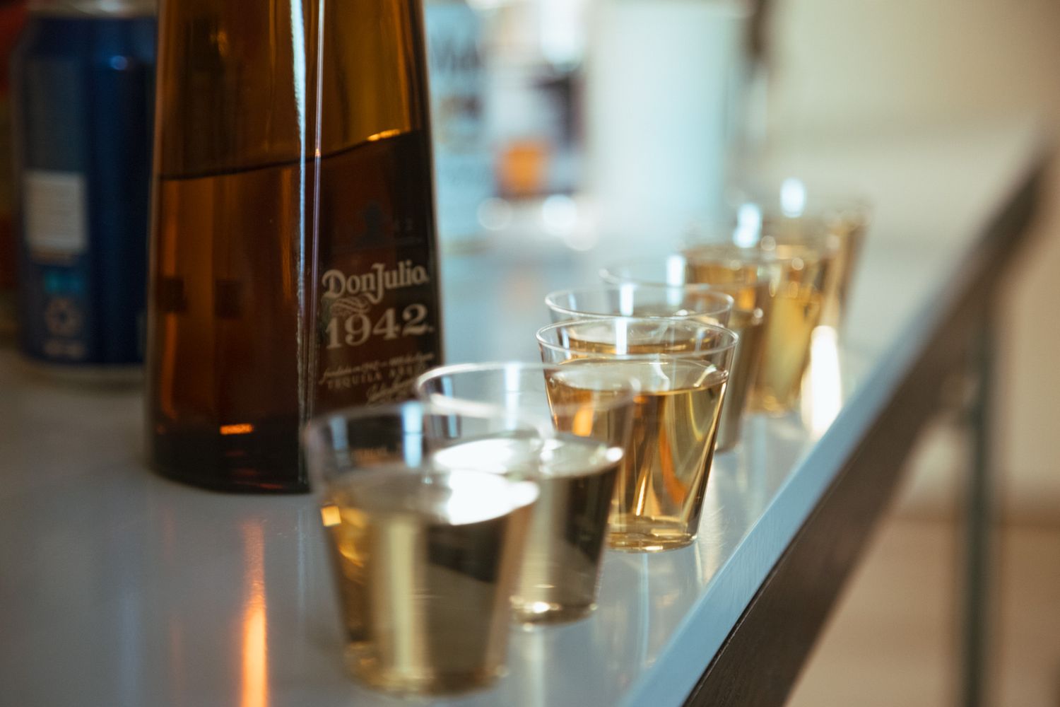 Don Julio 1942 tequila bottle with shot glasses lined up on bar at wedding reception.