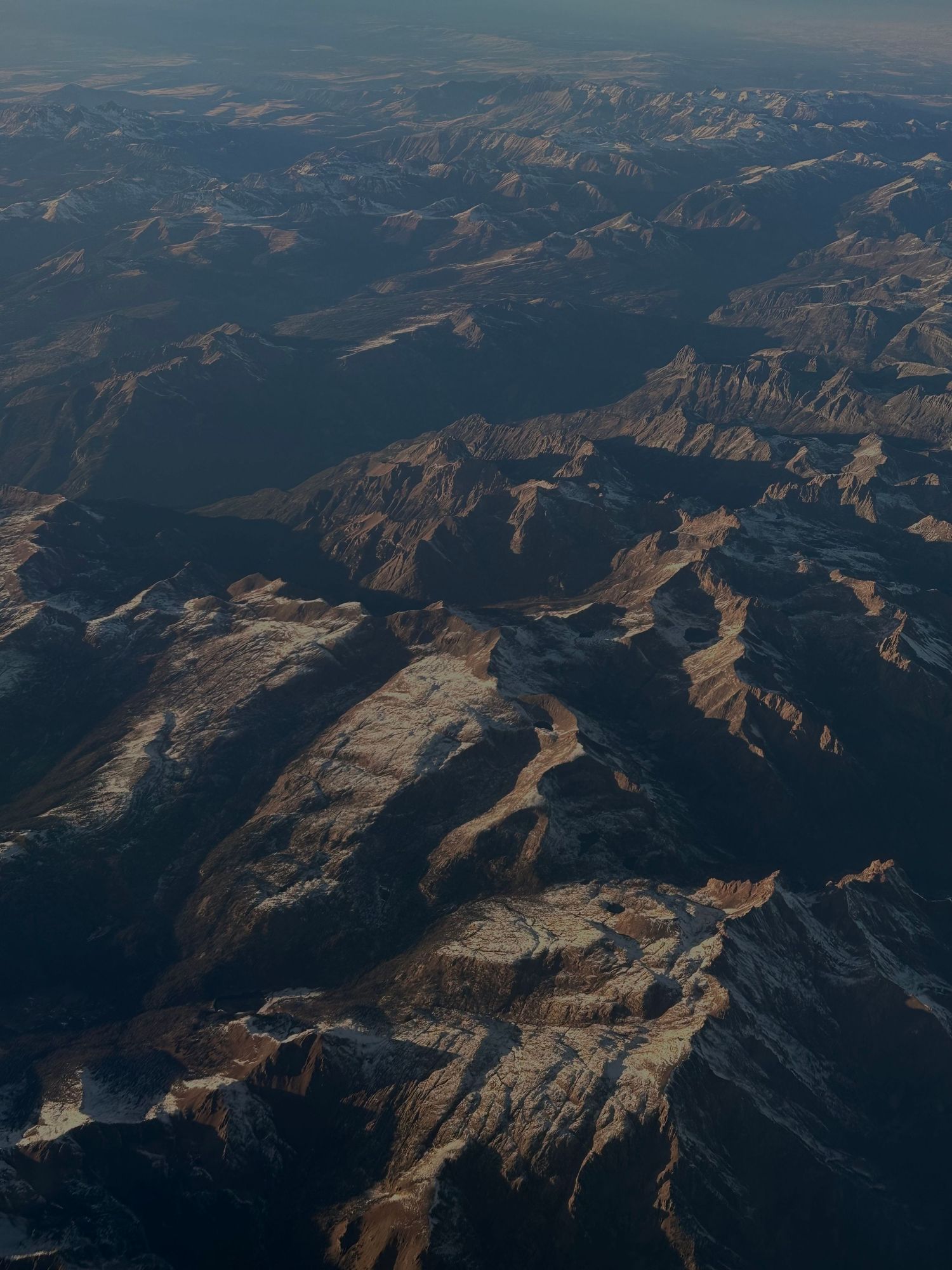 Aerial view of snow-capped mountain ranges and valleys from high altitude.