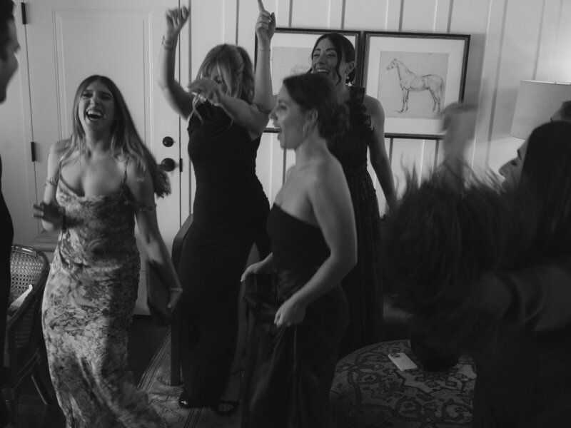 Group of people dancing and celebrating at a party in black and white.