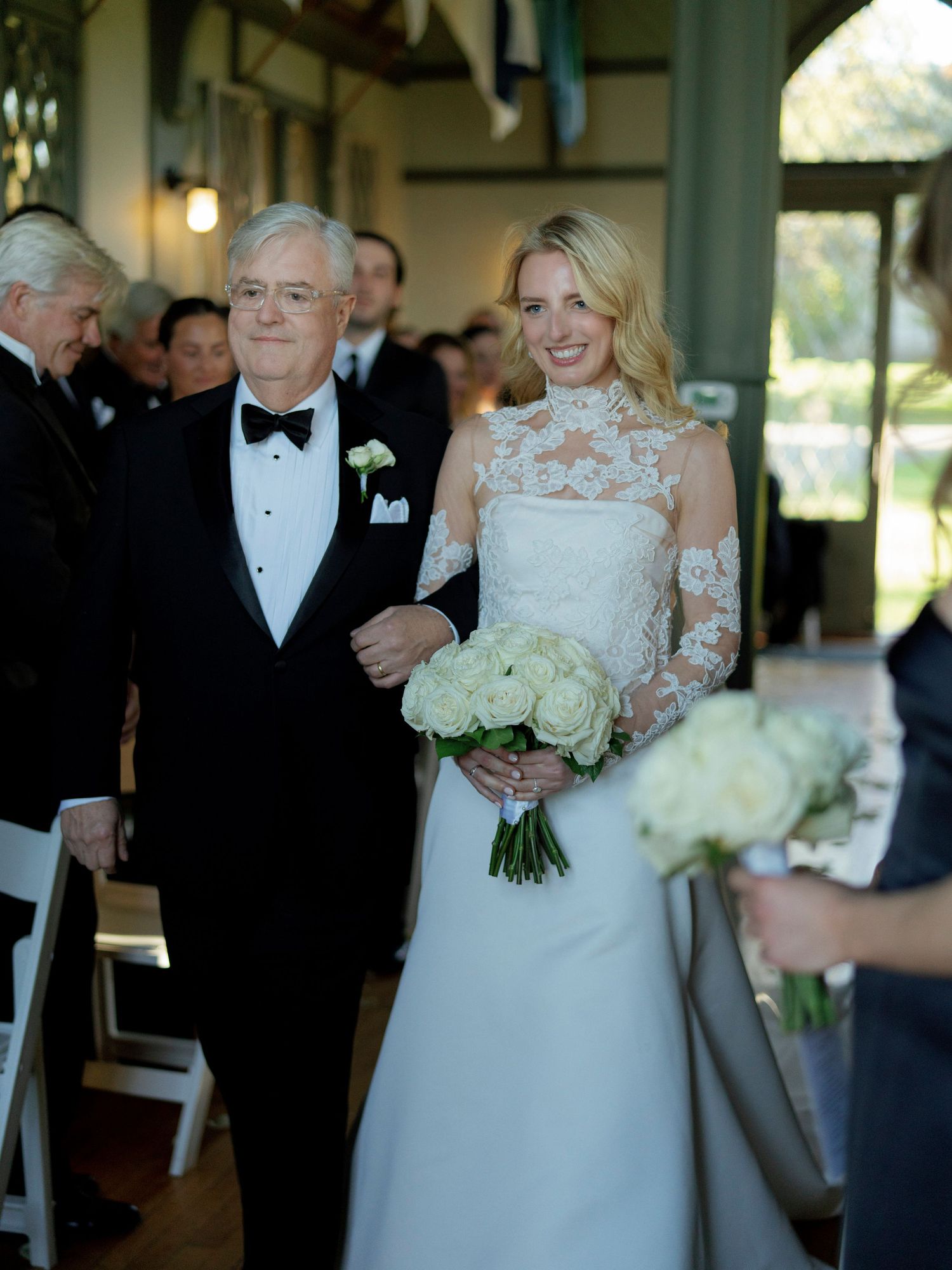Wedding ceremony processional in an elegant venue with white floral bouquet and formal attire.