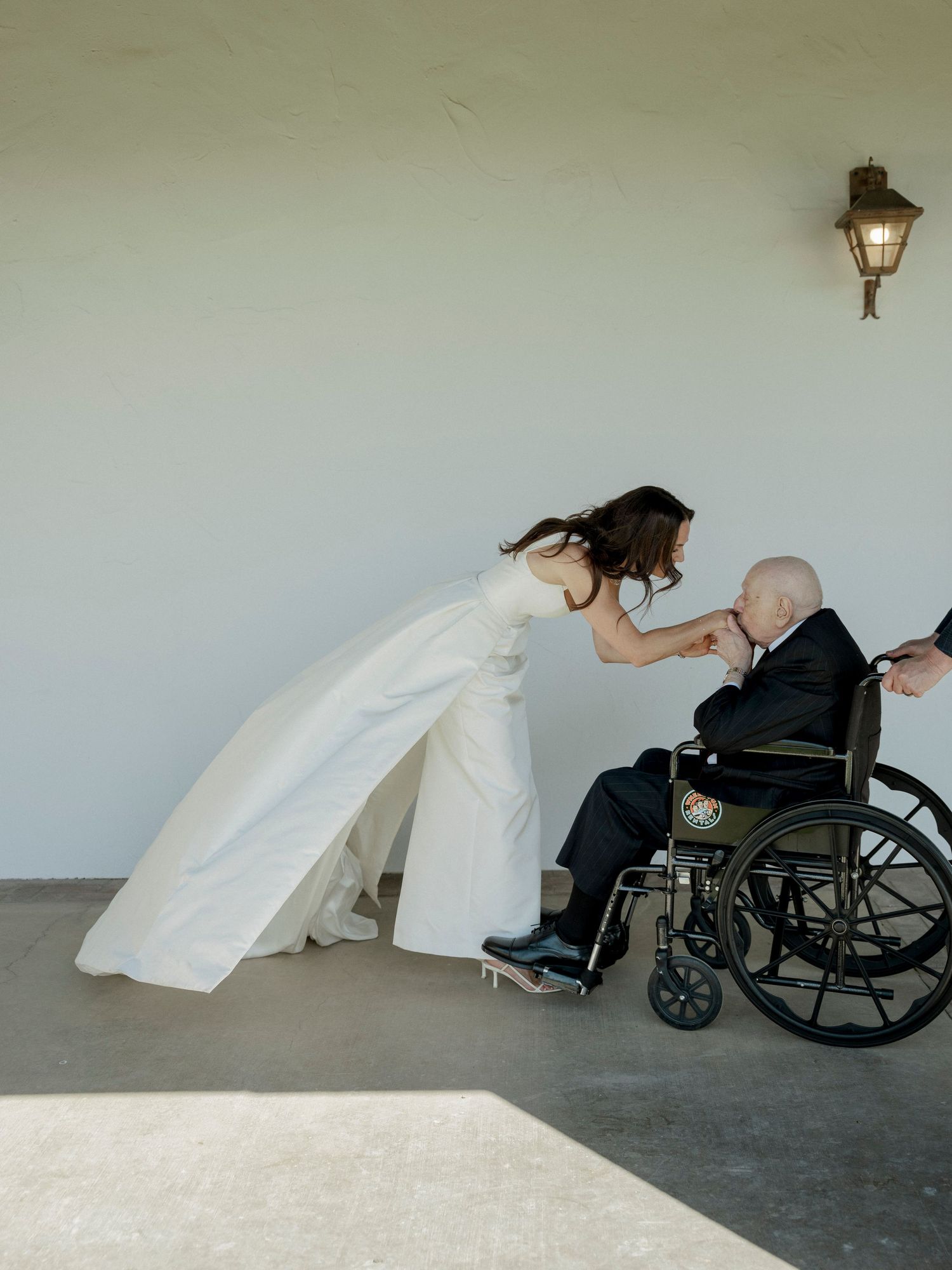 A touching wedding moment between a couple, with one person in a wheelchair.