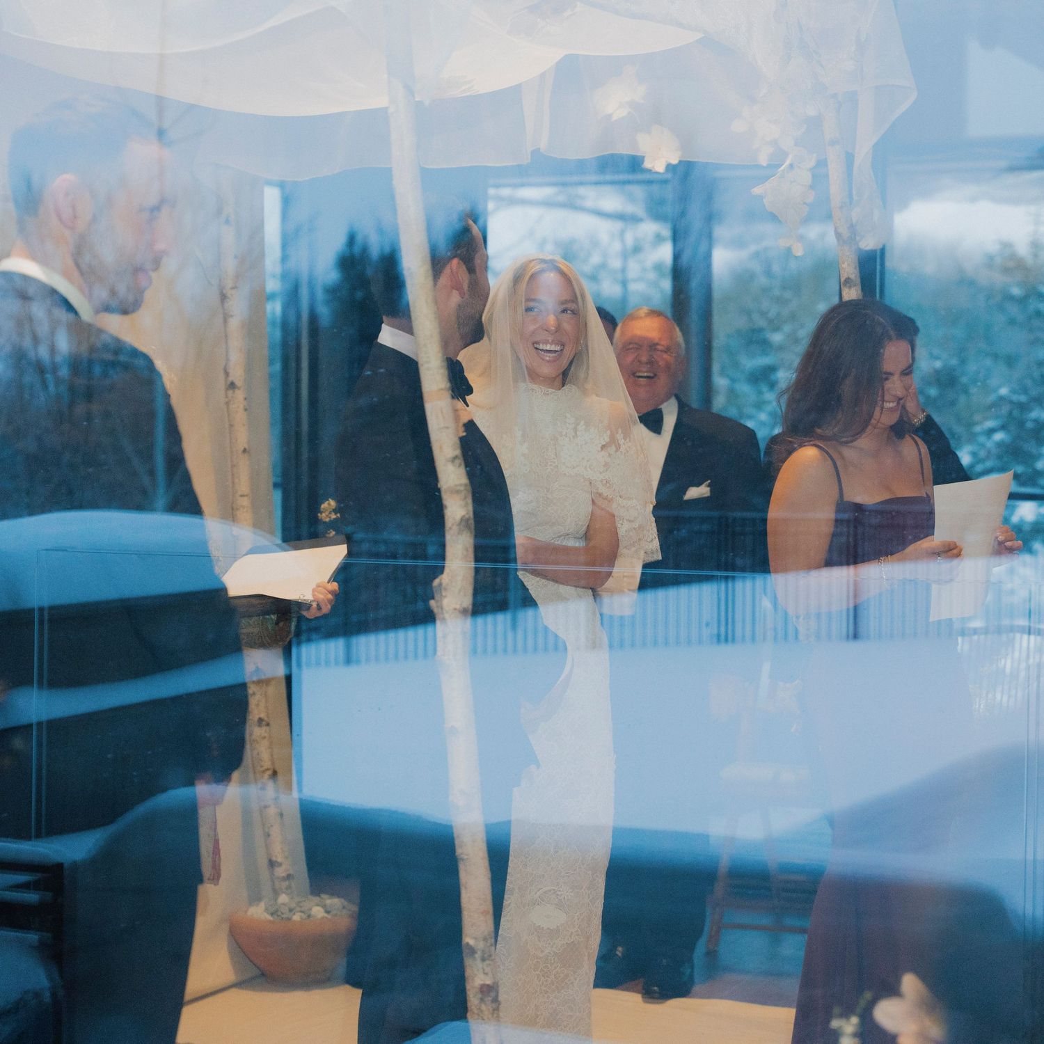 Wedding celebration scene reflected in window glass with ethereal white draping.