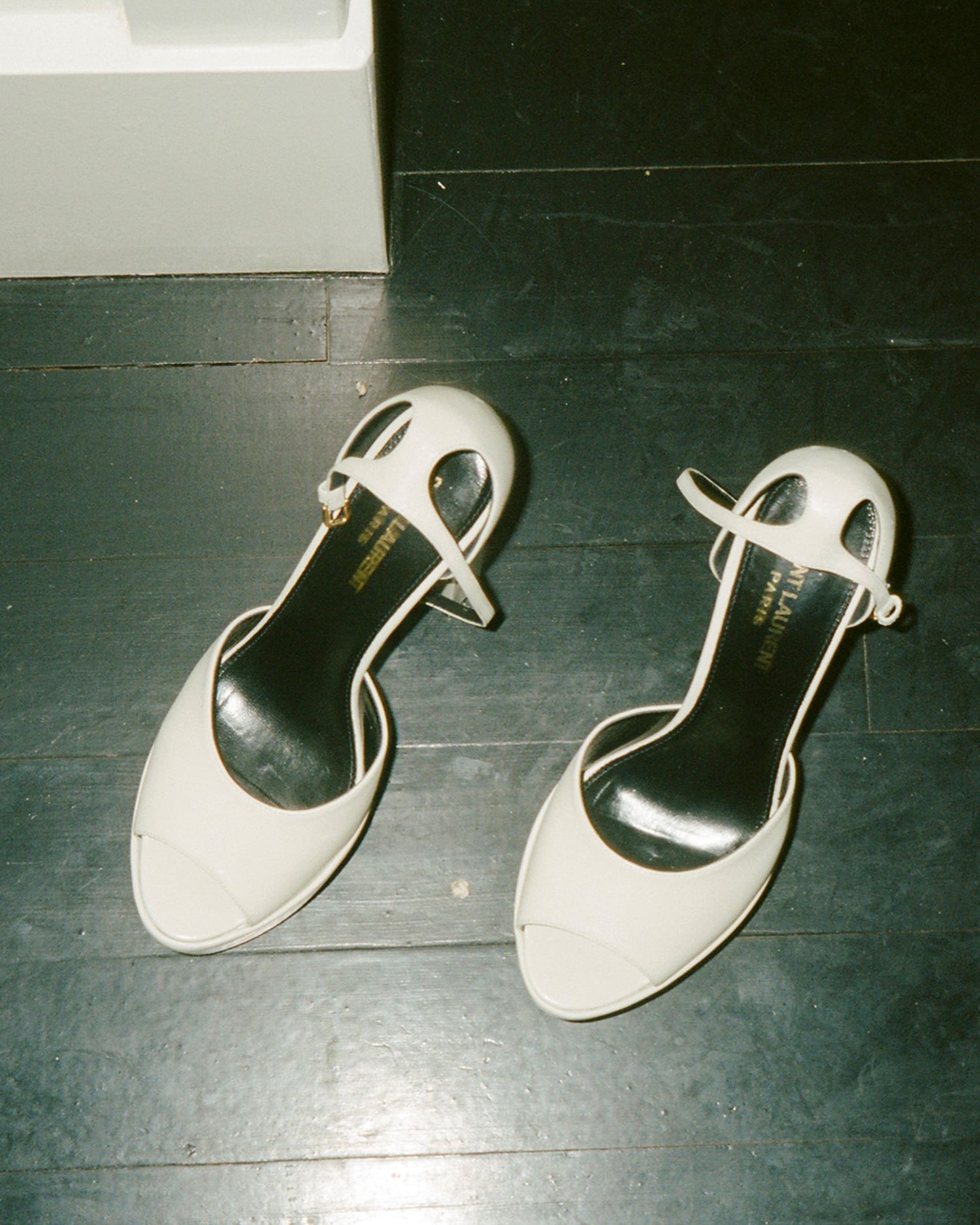 White bridal shoes arranged on a dark wooden floor.