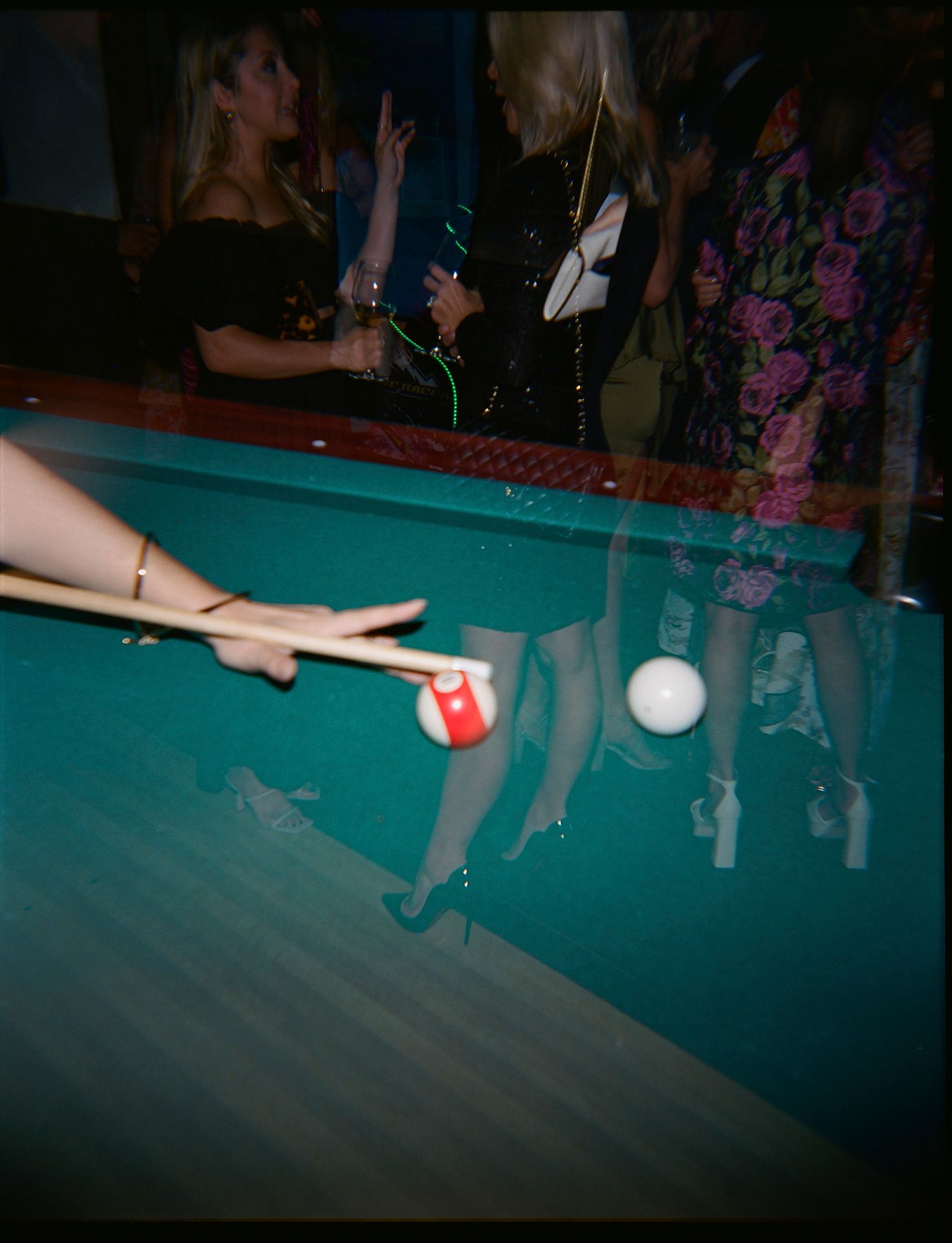 Blurred motion shot of a pool table with billiard balls and cue stick.