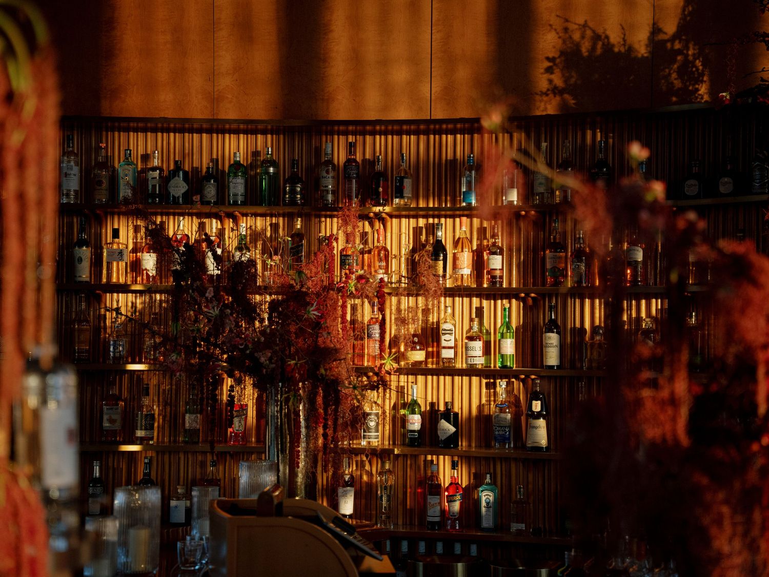 Dimly lit bar interior with glowing bottles and decorative lighting creating an atmospheric scene.