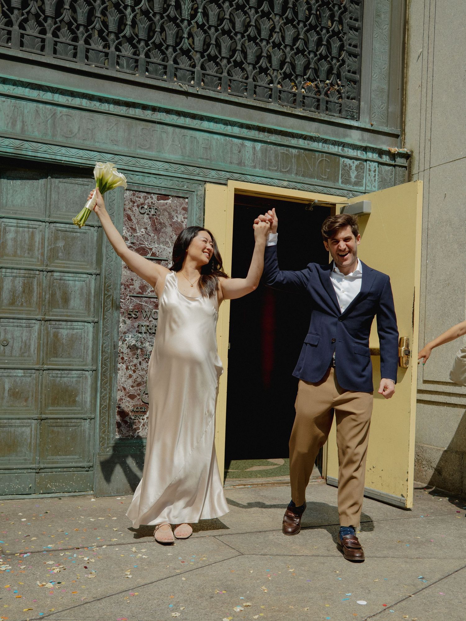 A joyful couple celebrates while exiting through vintage doors onto stone steps.