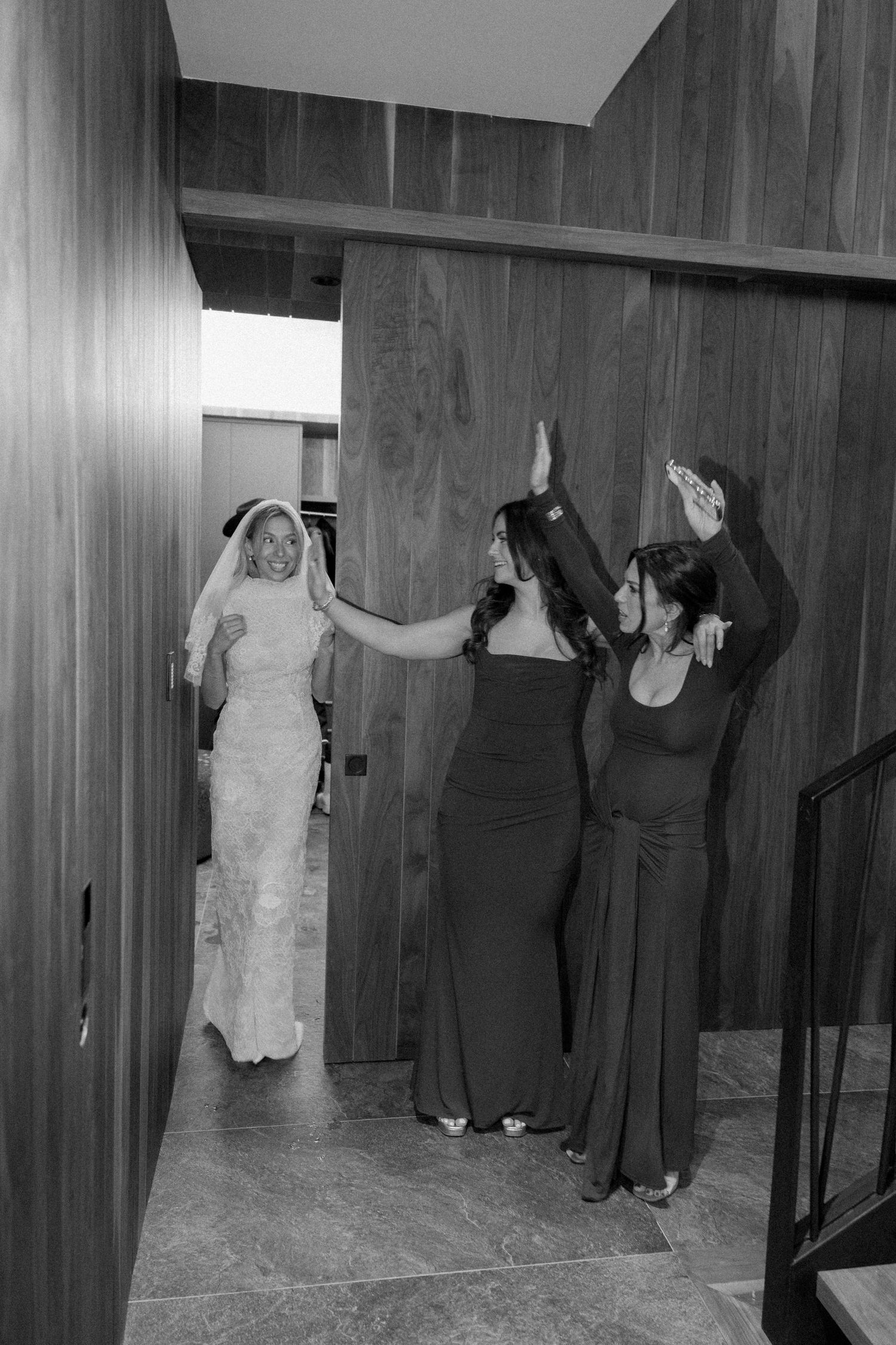 Black and white wedding scene in a wood-paneled hallway.