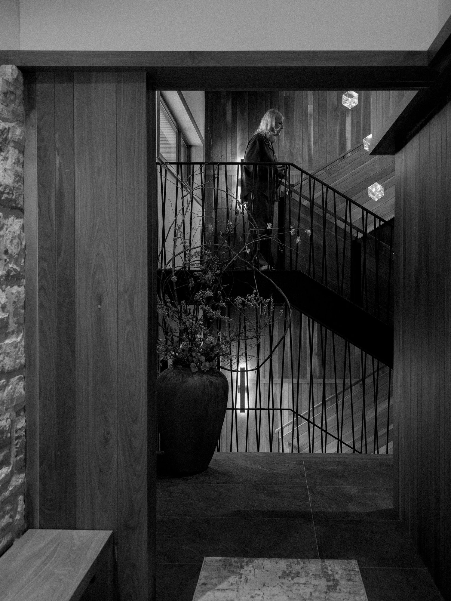 Black and white photo of a spiral staircase with wooden paneled walls.