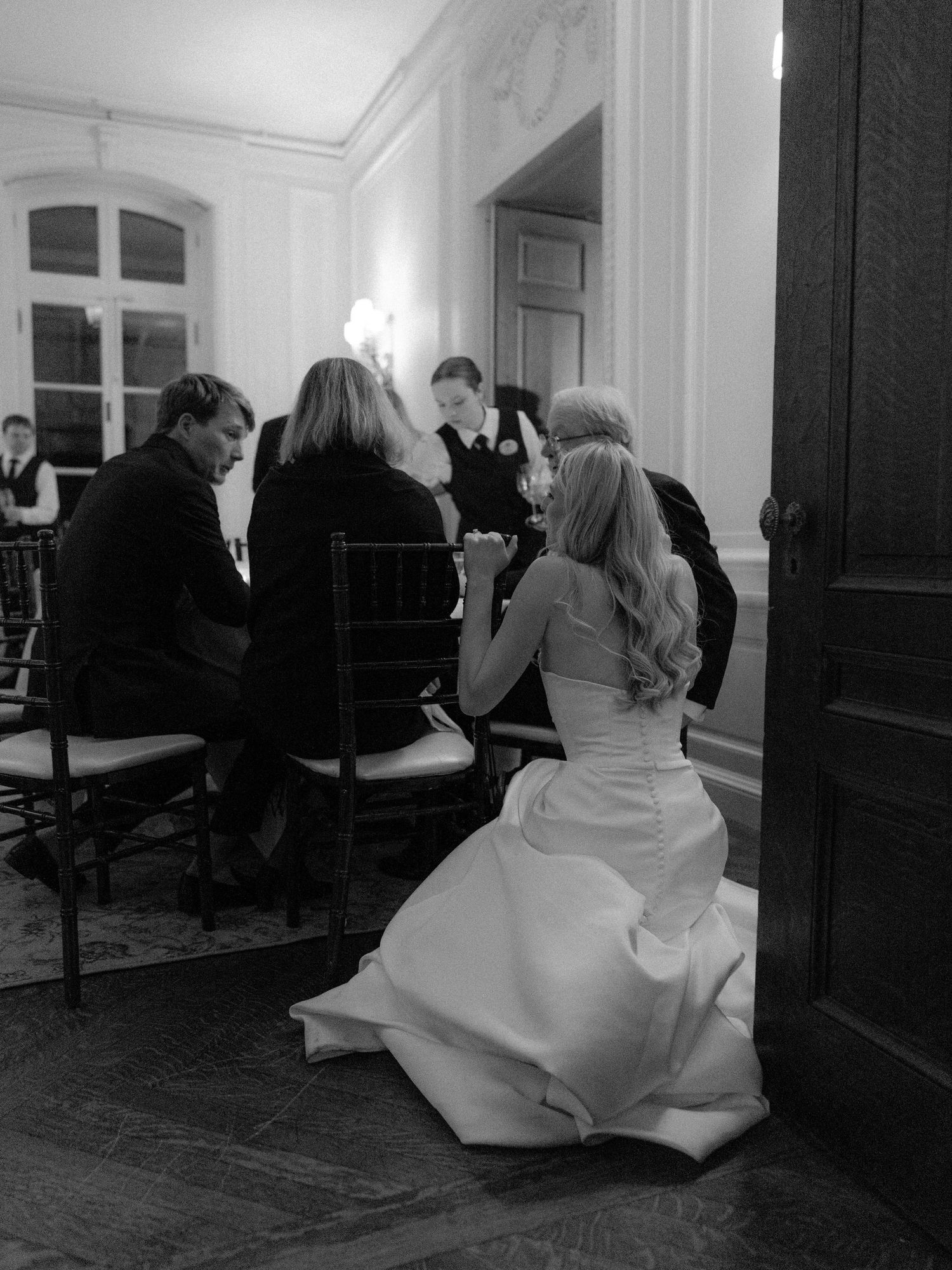 Black and white sequence showing movement and laughter in a formal interior space.