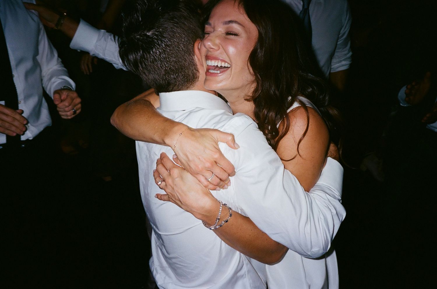 Joyful celebration with people embracing and dancing at a wedding reception.